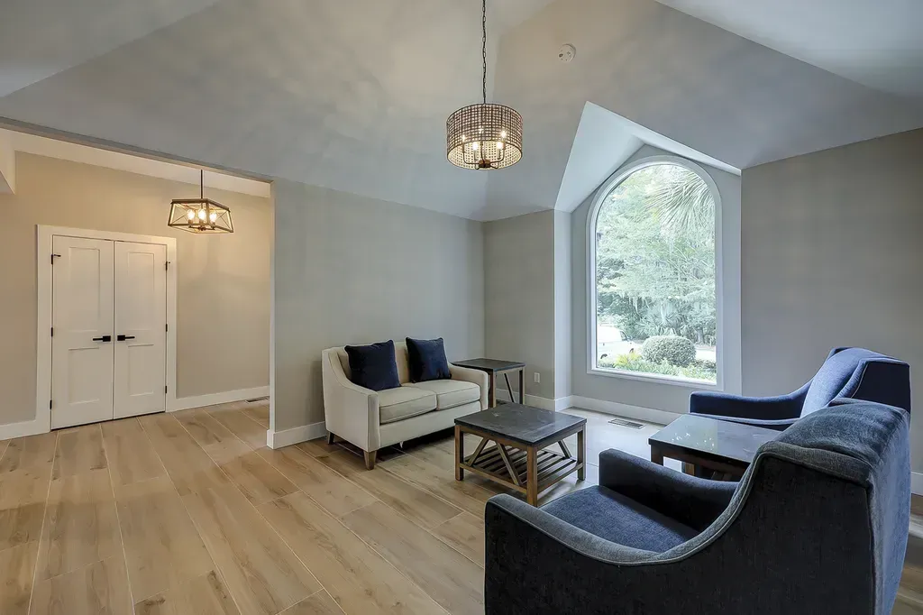 6 Planters - After: Living room with a high ceiling, two couches, and a large arched window.