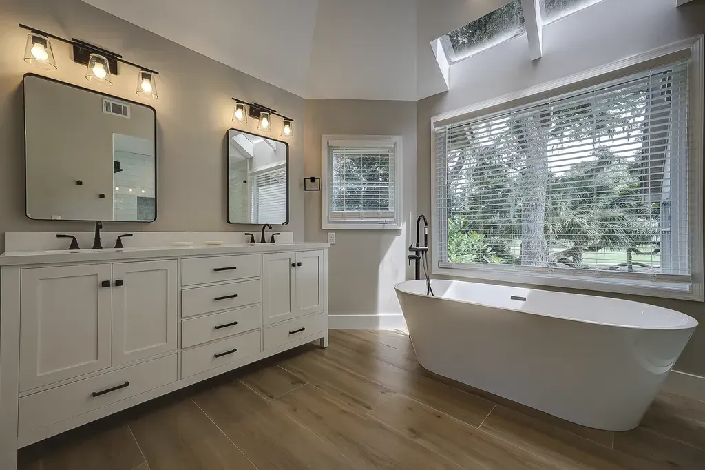 6 Planters - After: Modern bathroom with white cabinets, freestanding tub, and large window with blinds.