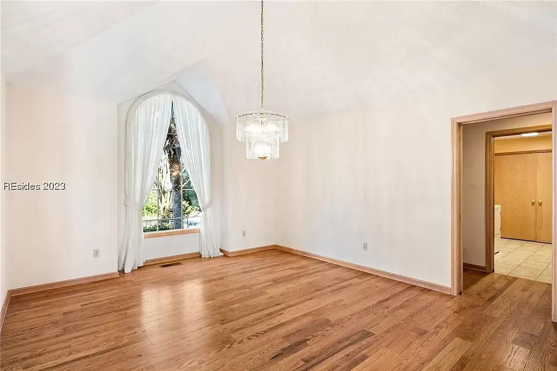 6 Planters - Before: Empty room with wood floors, chandelier, arched window with white curtains, and a doorway.