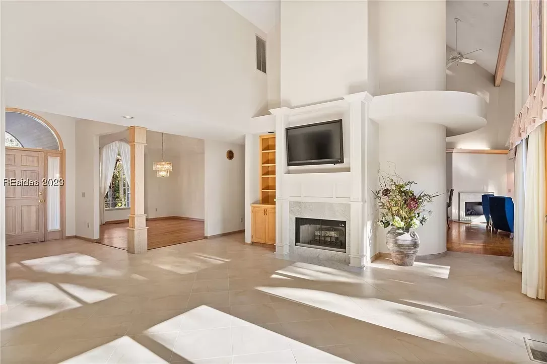 6 Planters - Before: Spacious living room with fireplace, built-in shelves, TV, and arched doorways. Bright, natural light floods the interior.