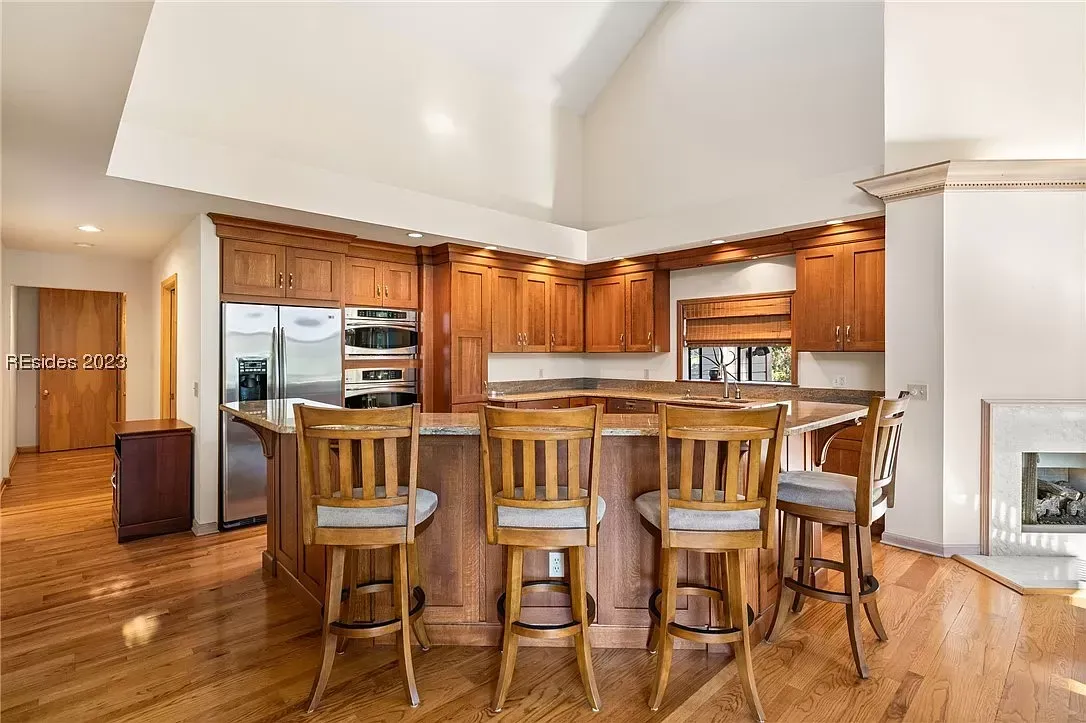 6 Planters - Before: Kitchen with wooden cabinets, island with bar stools, and hardwood floors.