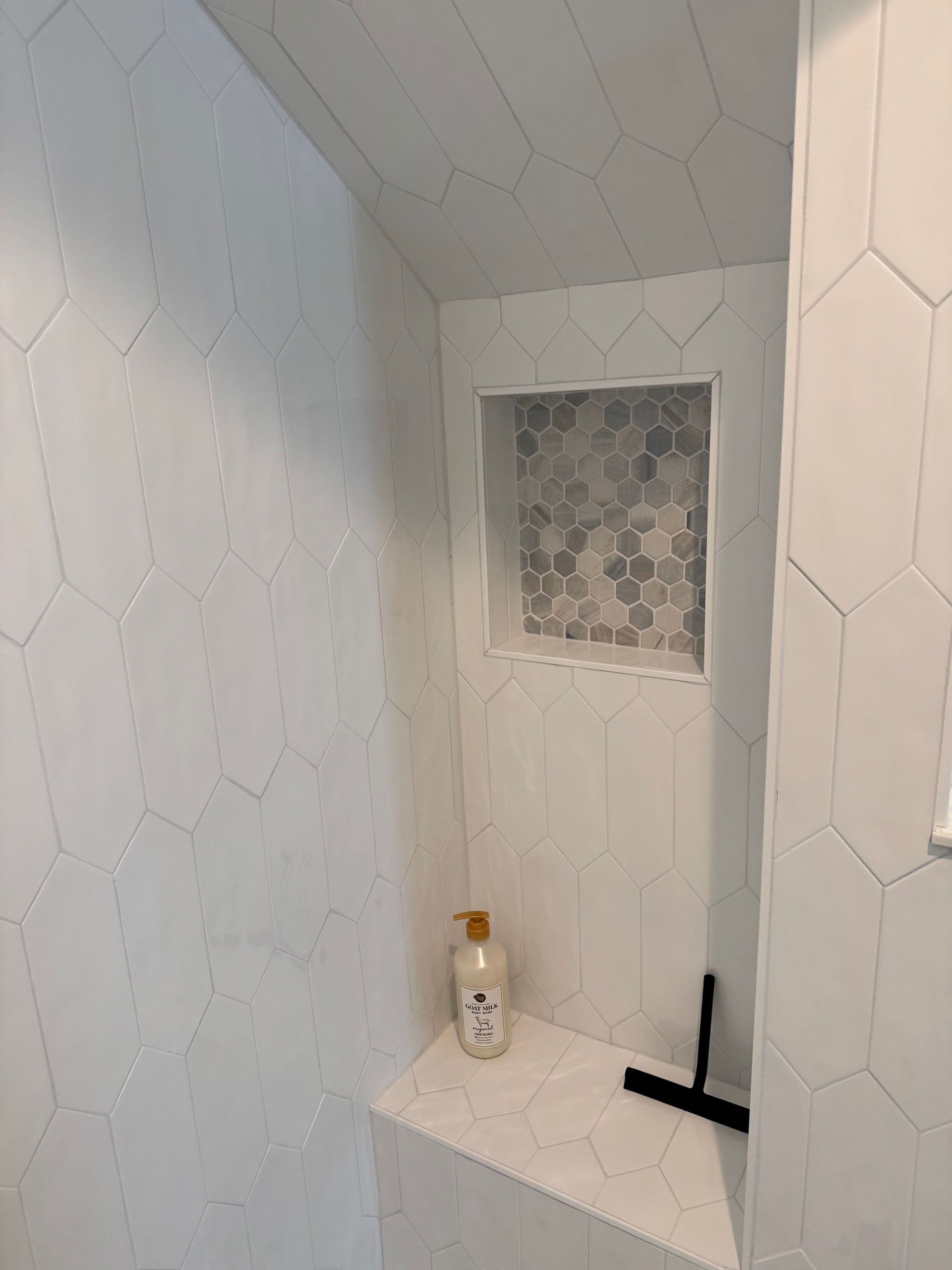 (18 Ensis) Port Royal Full Home Renovation: White-tiled shower interior with an inset shelf of gray mosaic tile and toiletries.