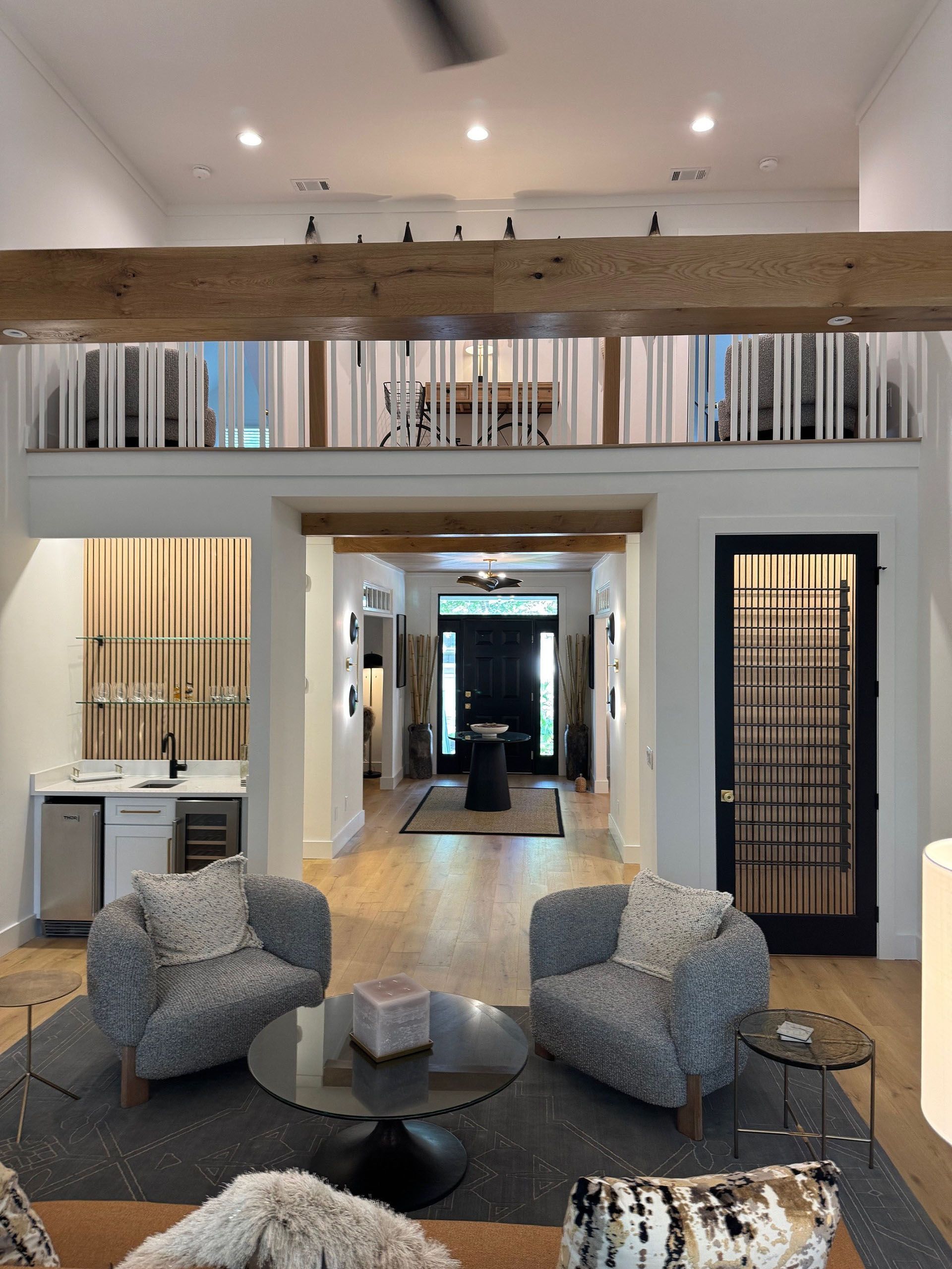 (18 Ensis) Port Royal Full Home Renovation: Spacious living area with two patterned armchairs, loft, and a black front door.