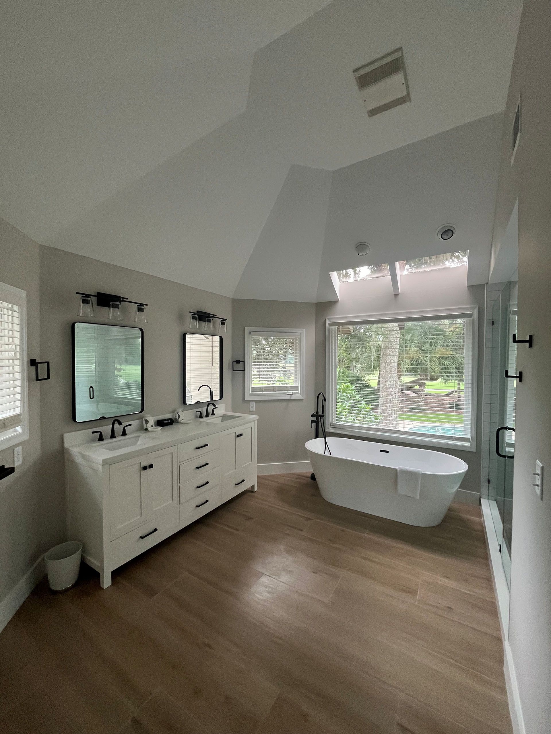 6 Planters - After: Modern bathroom with white double vanity, soaking tub, and natural wood floors.