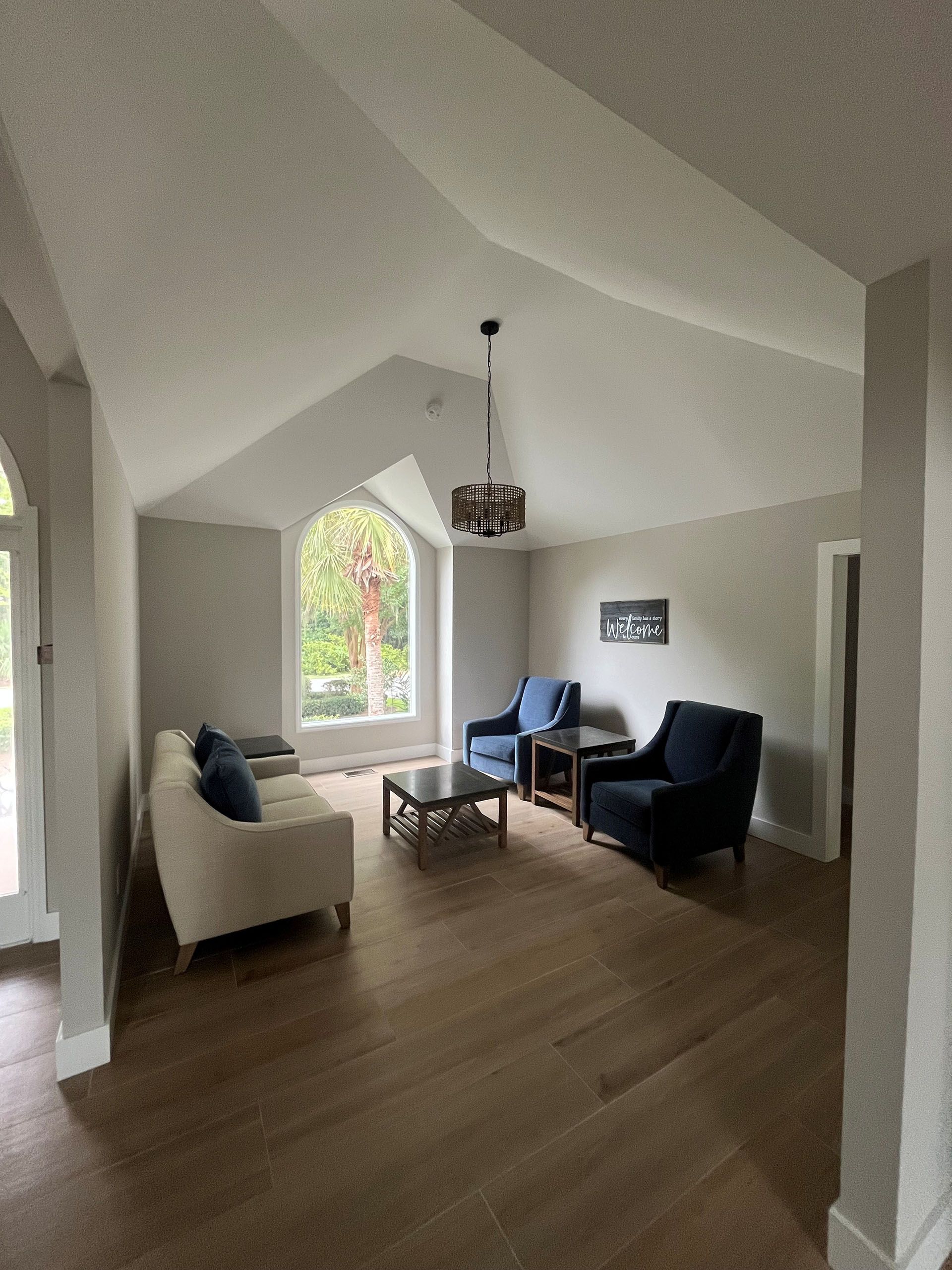 6 Planters - After: Living room with hardwood floors, vaulted ceiling, and furniture: a sofa, two chairs, and a coffee table.