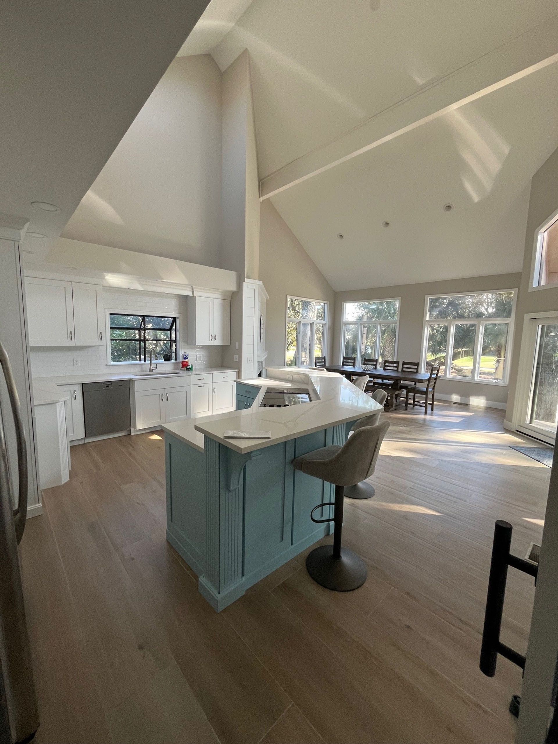 6 Planters - After: Spacious kitchen with blue island, white cabinets, and light wood floors, with natural light from large windows.