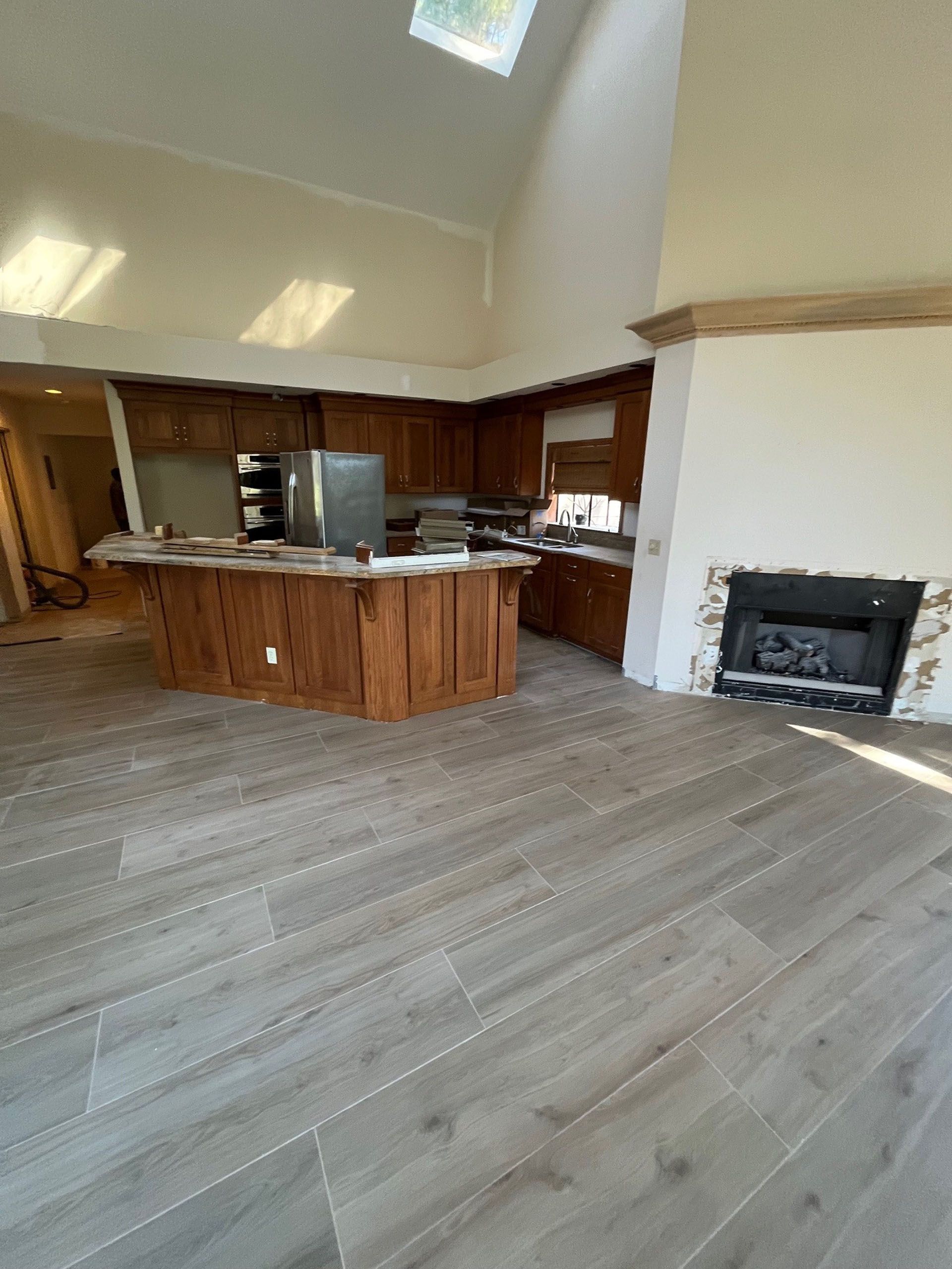 6 Planters - Before: Newly renovated kitchen with wood cabinets, center island, fireplace, and gray tile floors.