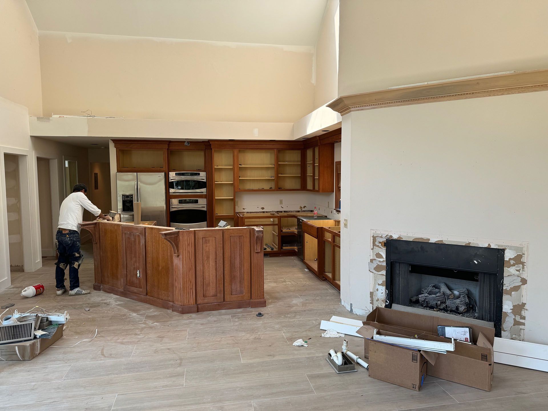 6 Planters - During: Kitchen under renovation with a worker, cabinets, fireplace, and exposed walls.