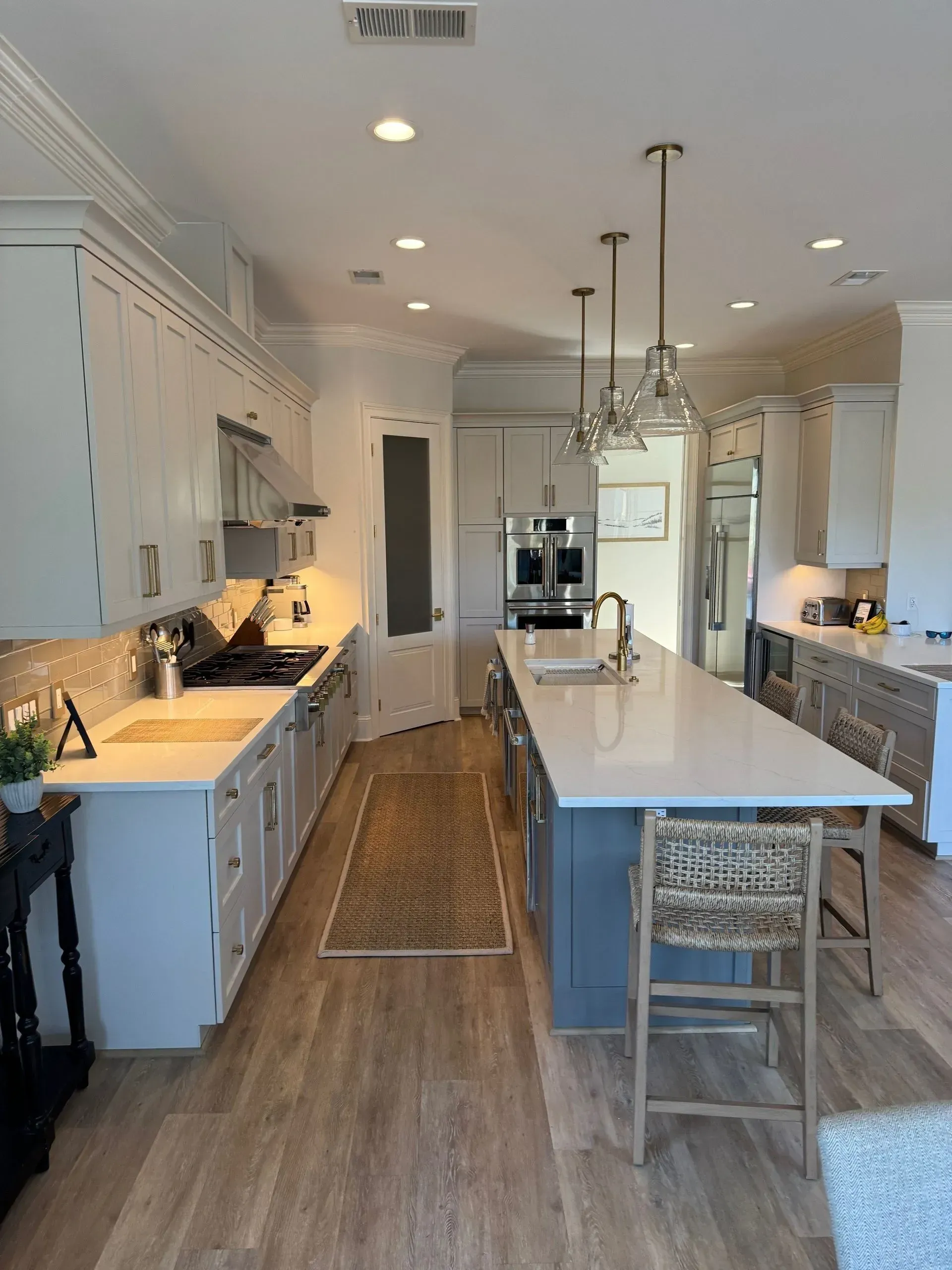 Wexford Home Remodel - After: Living room with bar area; three bar stools in front of an archway with dark cabinetry.