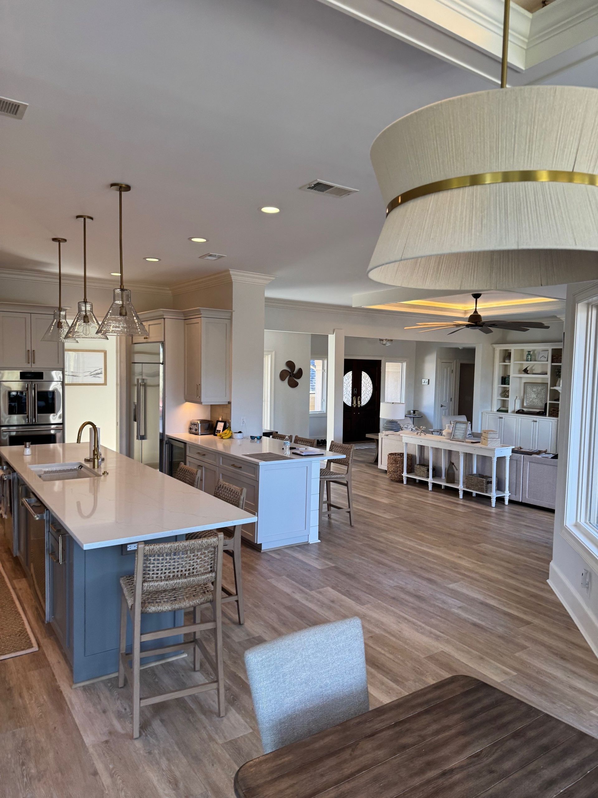 Spacious open-concept kitchen with islands and seating, leading to living and dining areas; light wood floors, neutral colors.