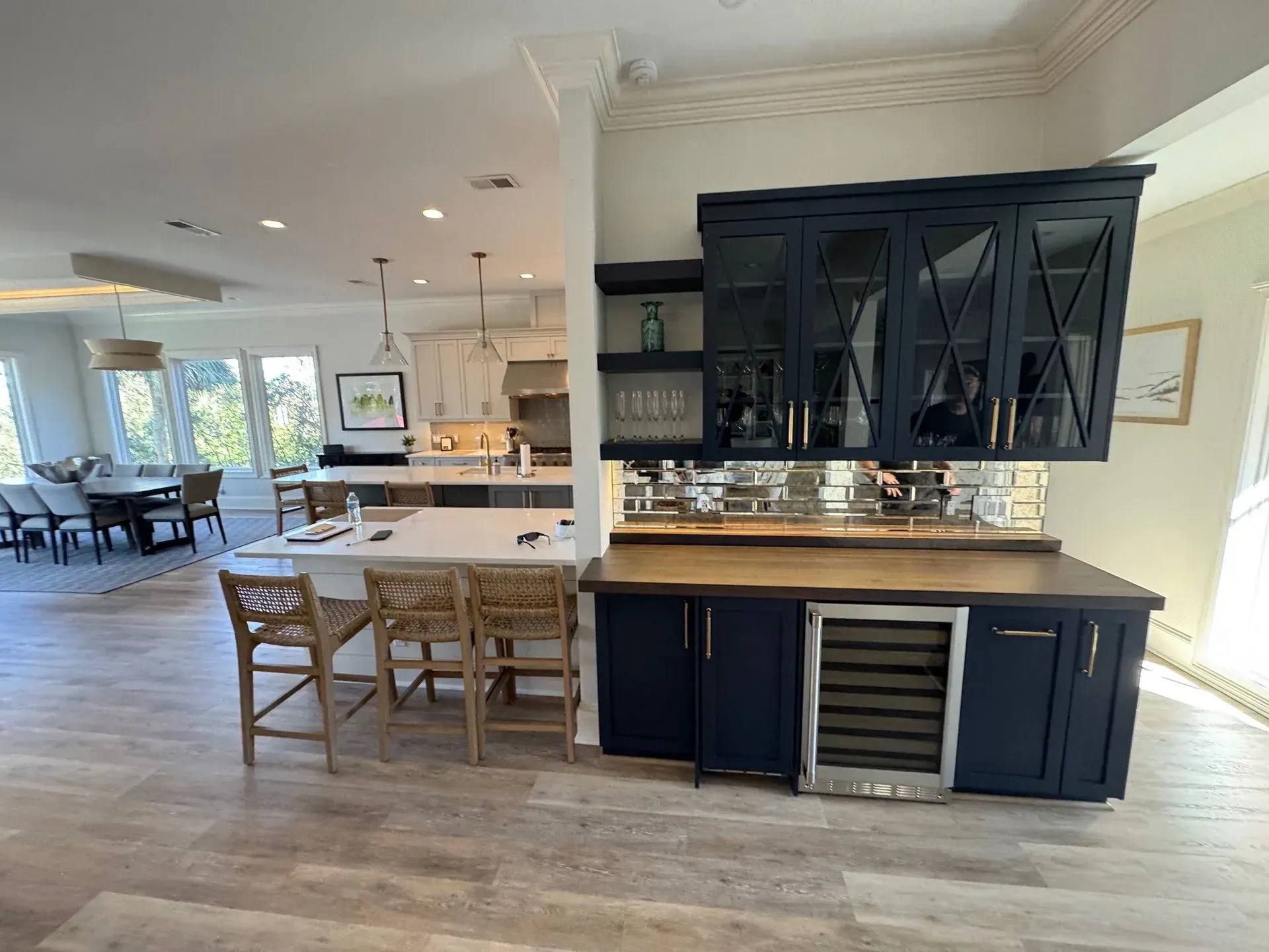 Open-concept kitchen with a navy blue bar area, a light wood floor, and a white kitchen in the background.