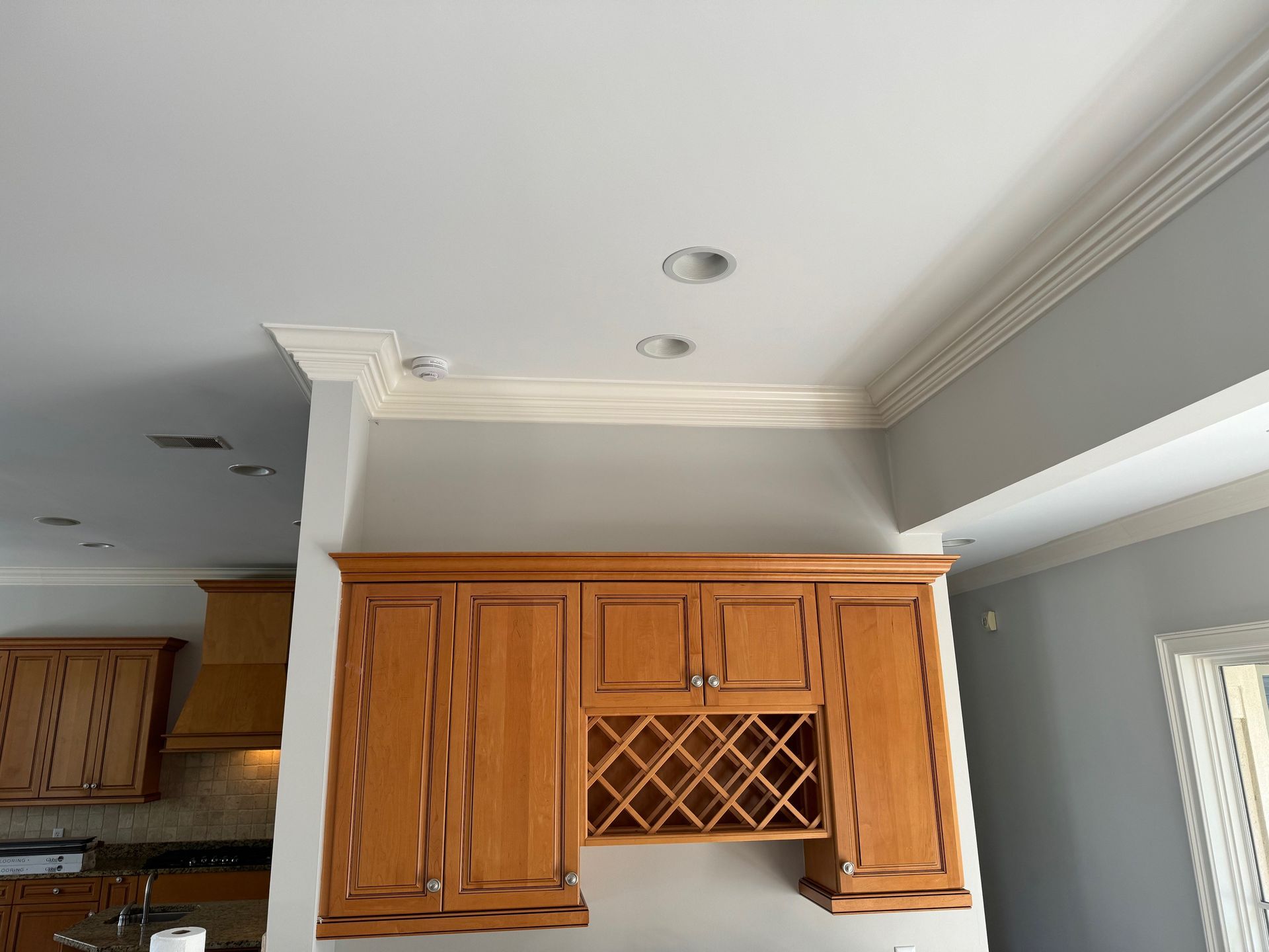 Kitchen cabinets with a wine rack, crown molding, and recessed lighting.