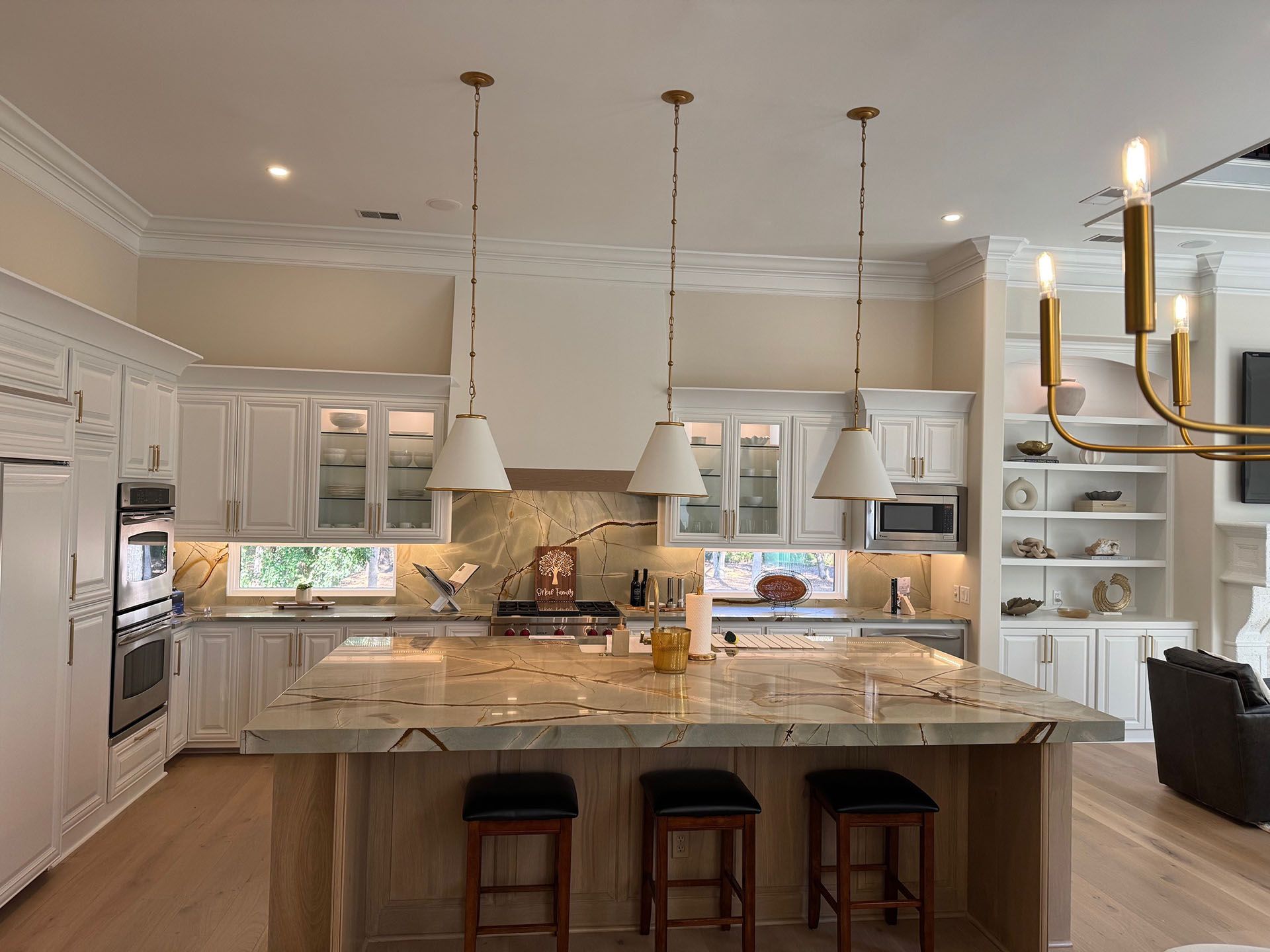 Wexford Home Remodel - After: Elegant white kitchen with island, pendant lights, and granite countertops.