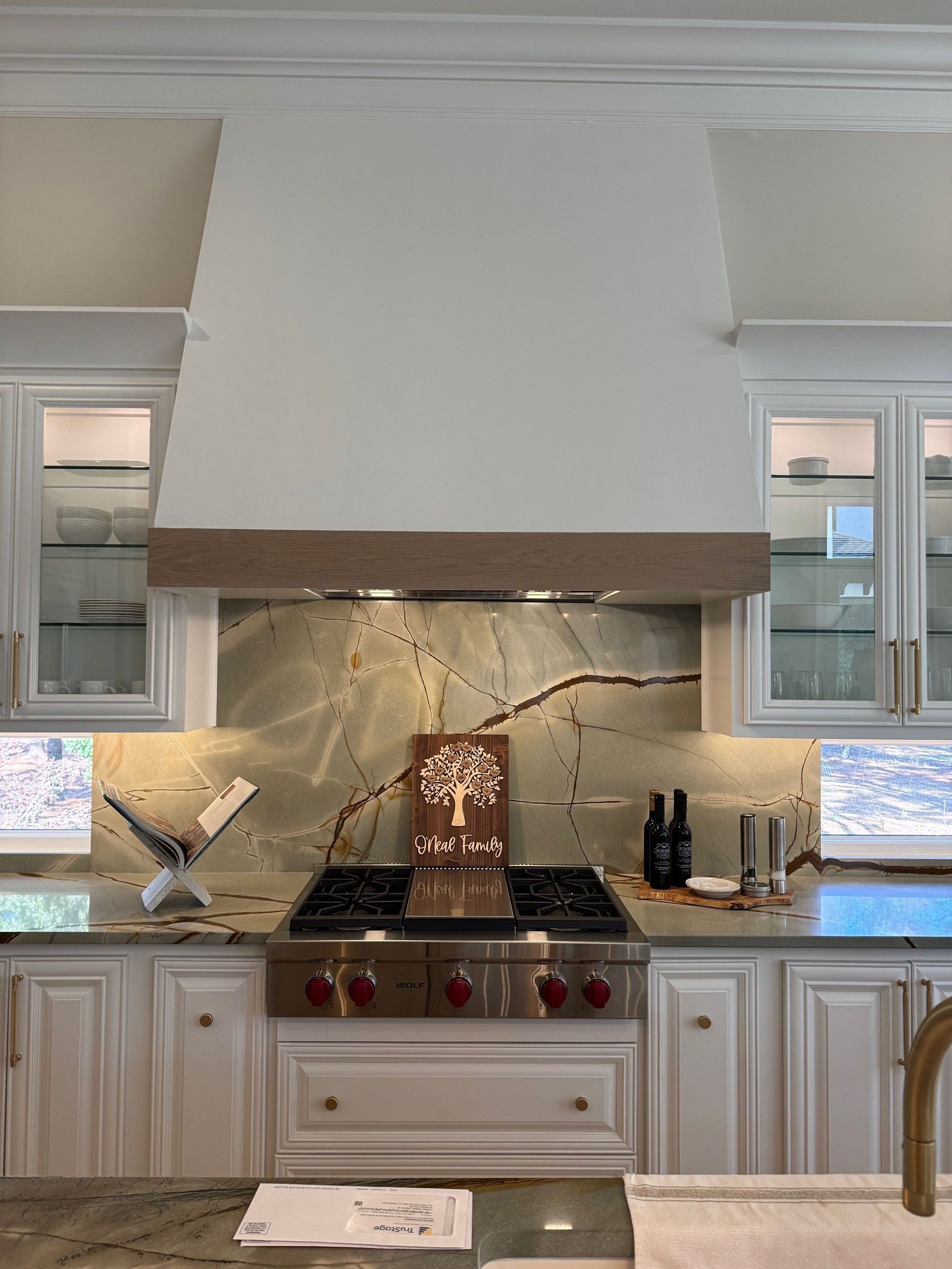 Wexford Home Remodel - After: White kitchen with stove, range hood, and green patterned backsplash.