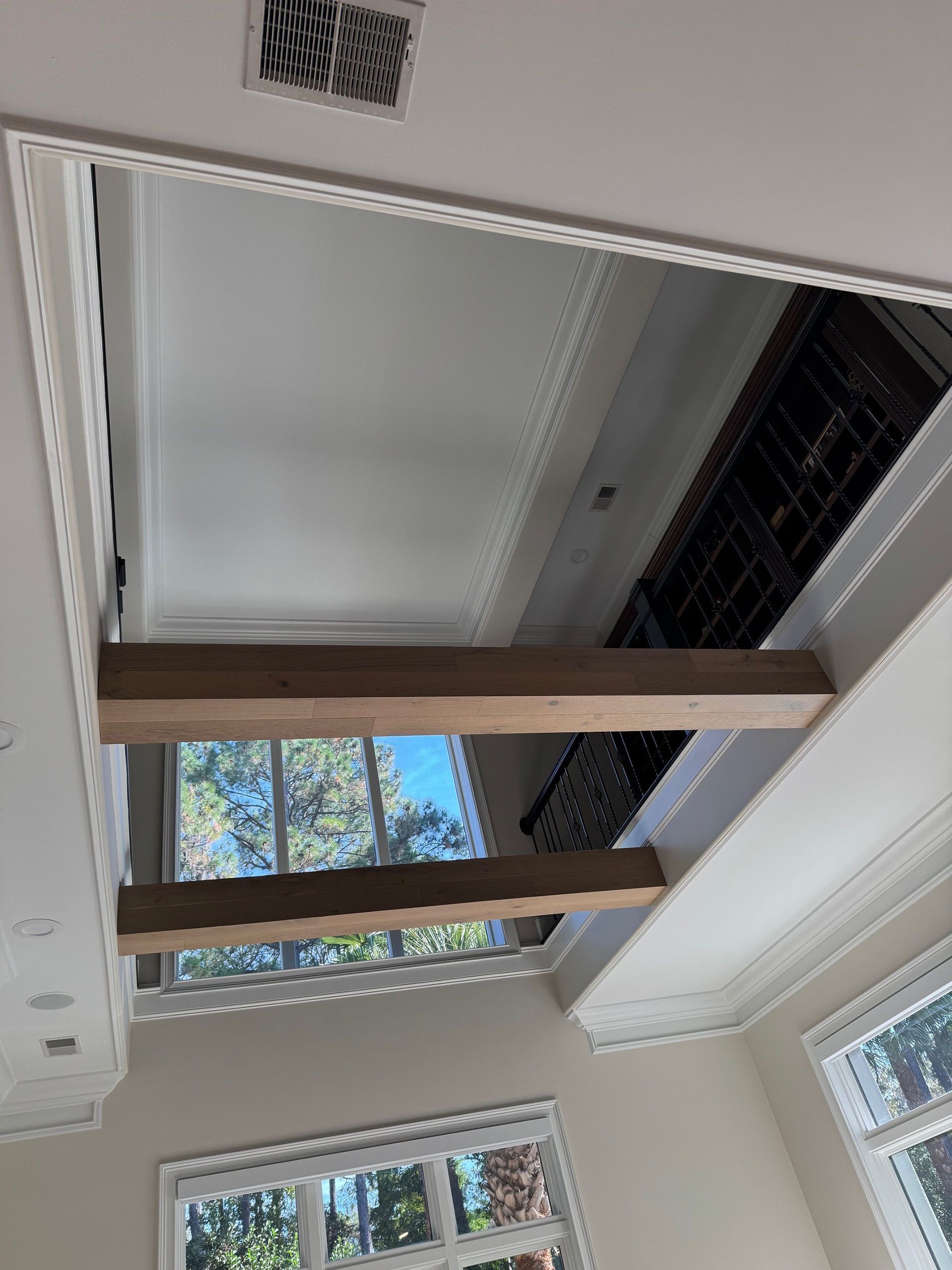 Wexford Home Remodel - After: Ceiling opening with two wooden beams and decorative trim. Sunlight streams through to the outdoor.