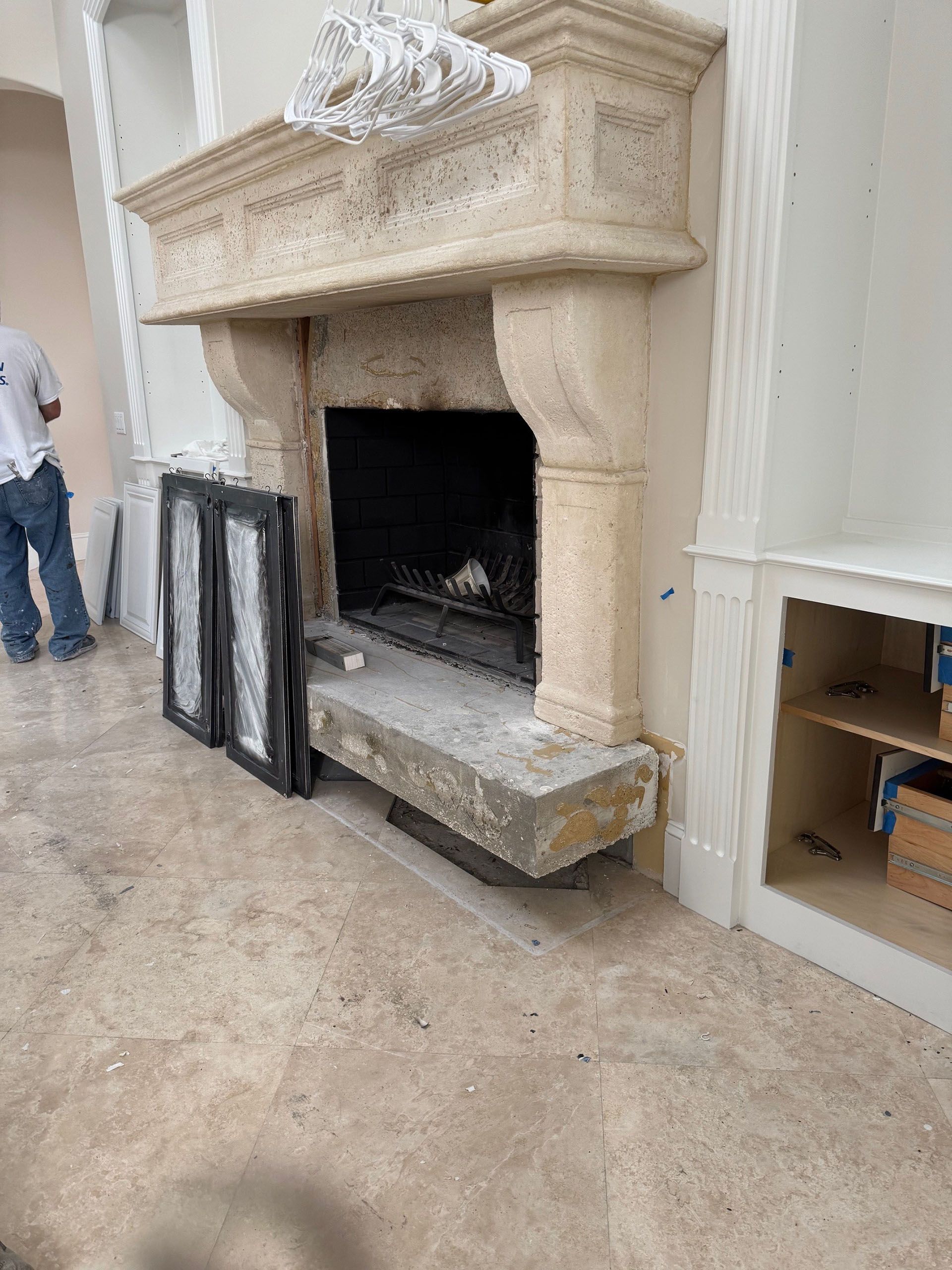 Wexford Home Remodel - Before: Stone fireplace in a room under construction, with a person standing nearby.