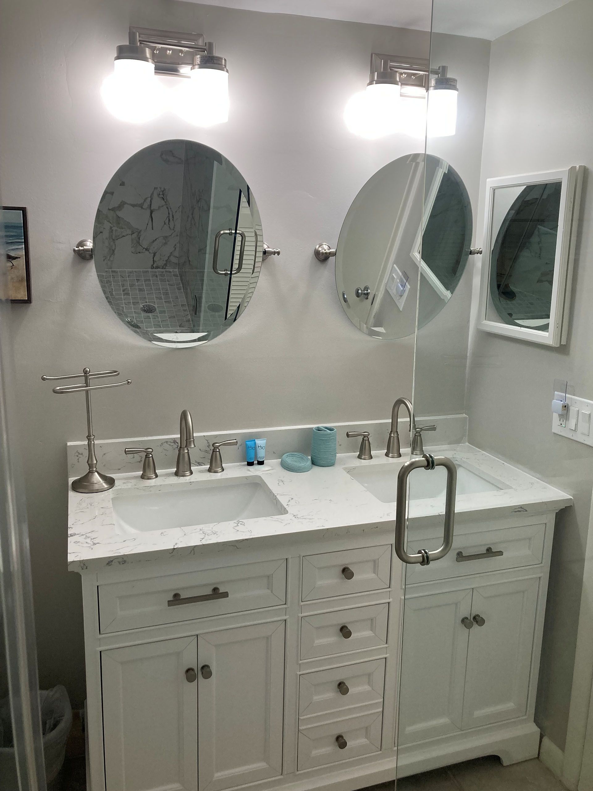 Miscellaneous Bathroom Projects - White double-sink bathroom vanity with round mirrors and overhead lighting; gray walls.