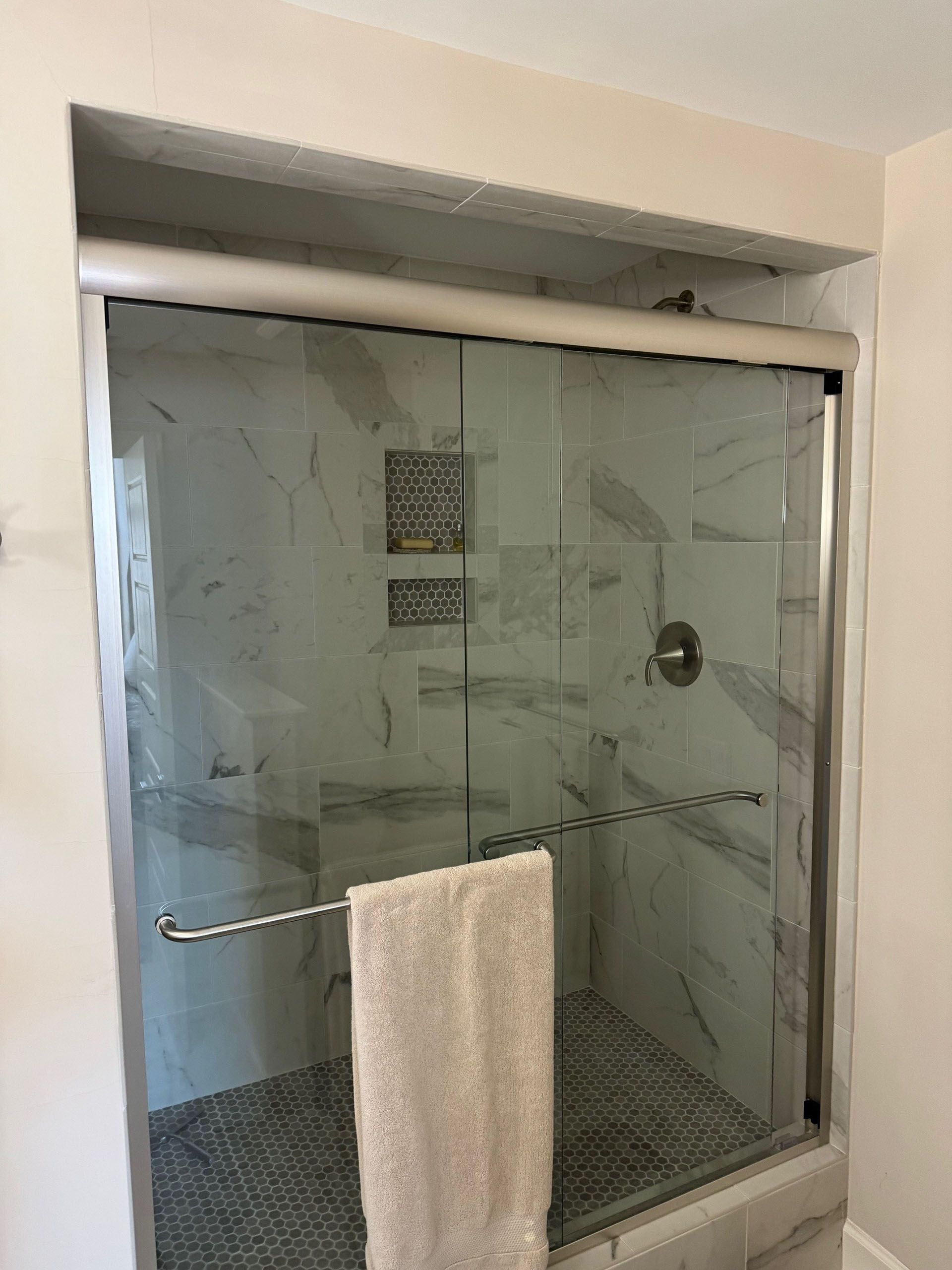 Miscellaneous Bathroom Projects - Shower with a marble tile pattern, glass doors, and a towel hanging on a bar.