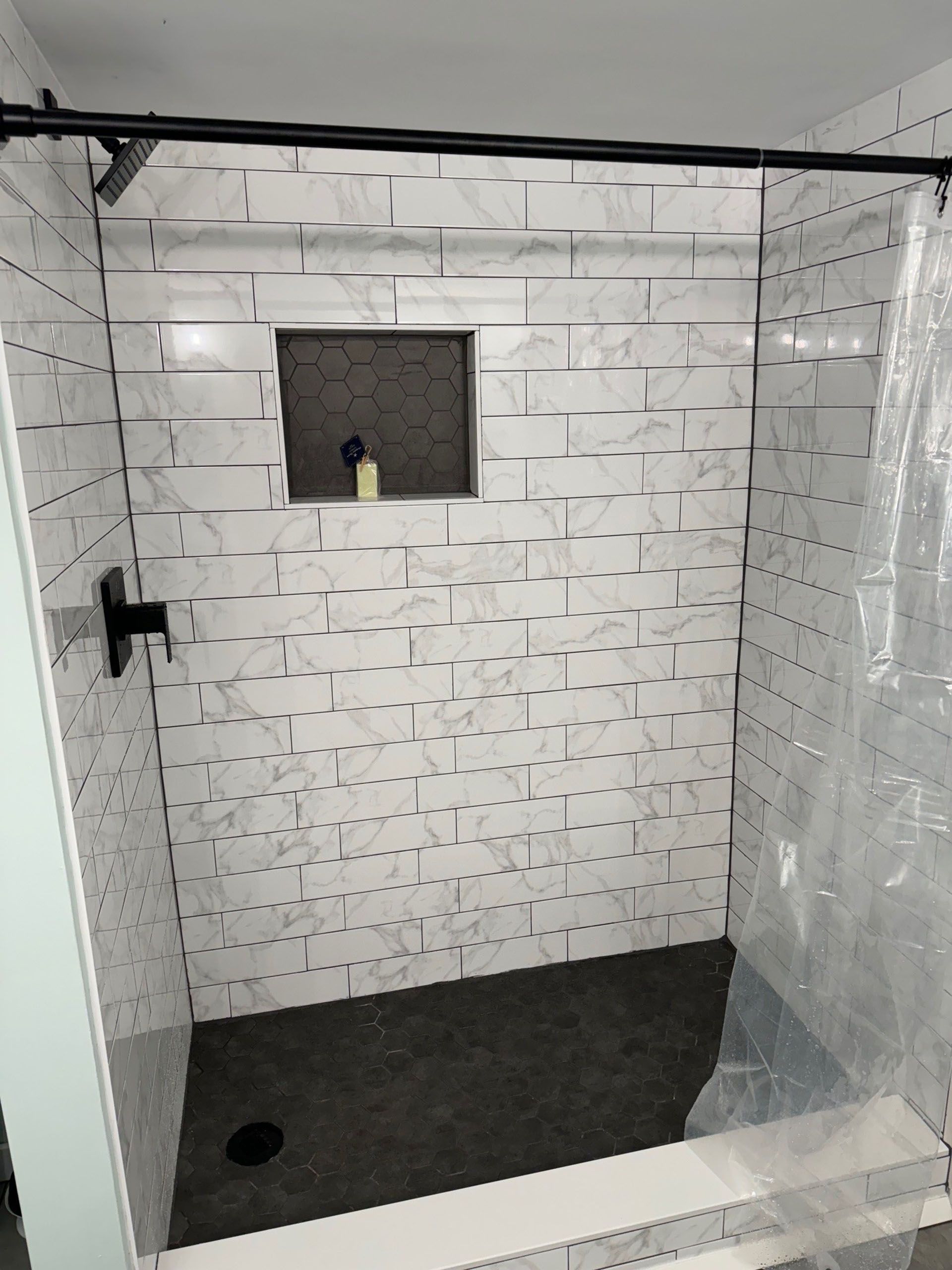 Miscellaneous Bathroom Projects - Shower with white marble-look tiles, black shower fixtures, and a recessed shelf.