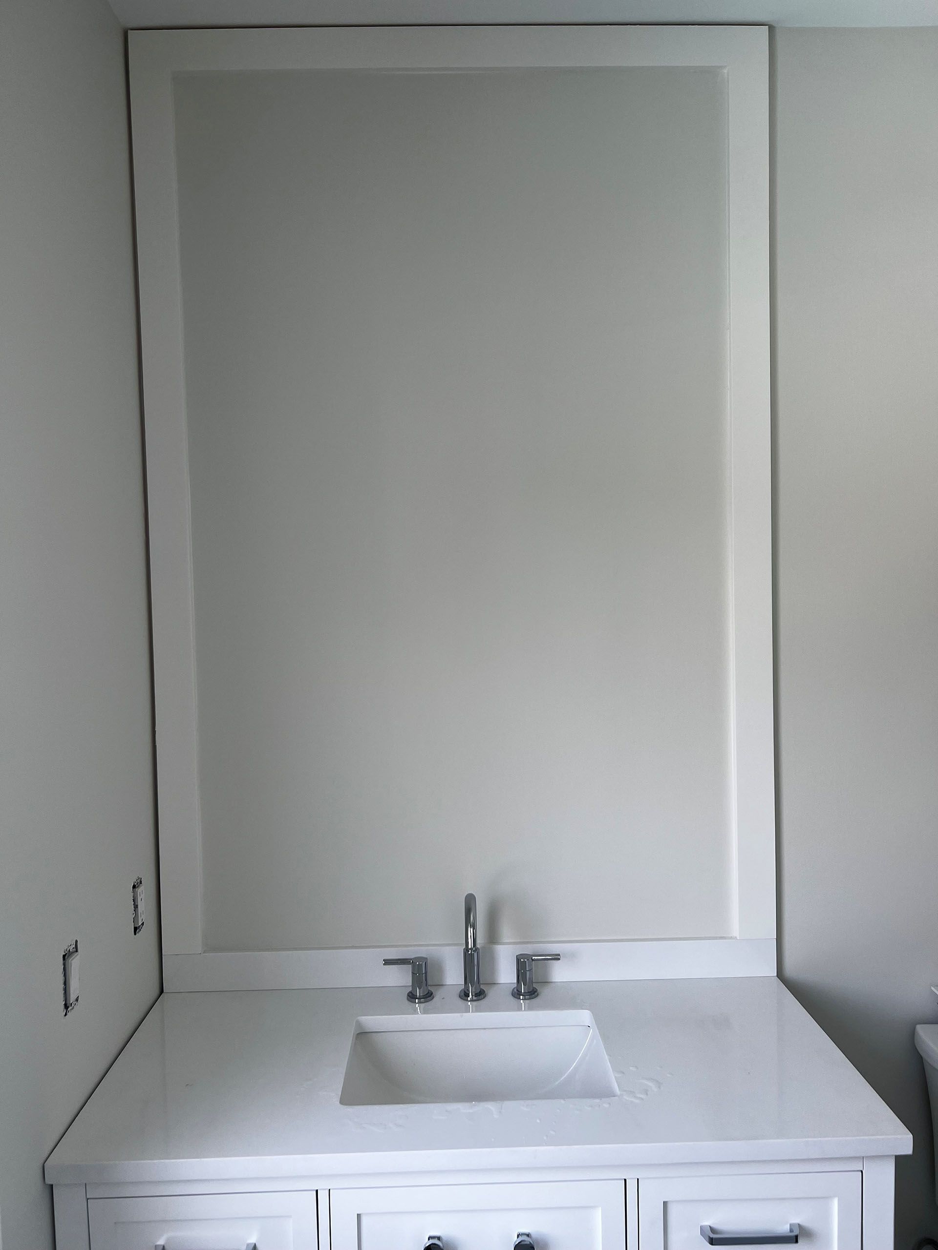 Miscellaneous Bathroom Projects - White bathroom vanity with sink and large framed mirror.