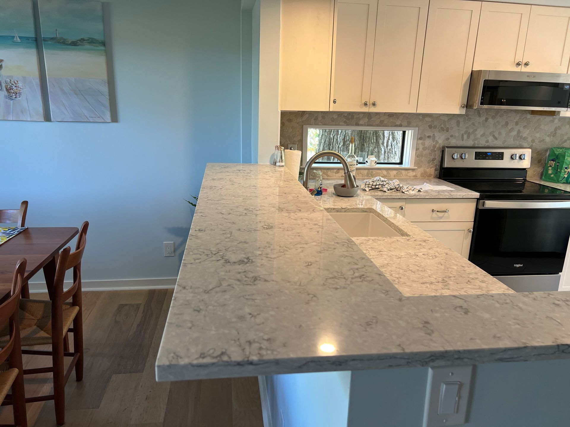 Kitchen with a light-colored countertop, white cabinets, and a microwave above the stove.