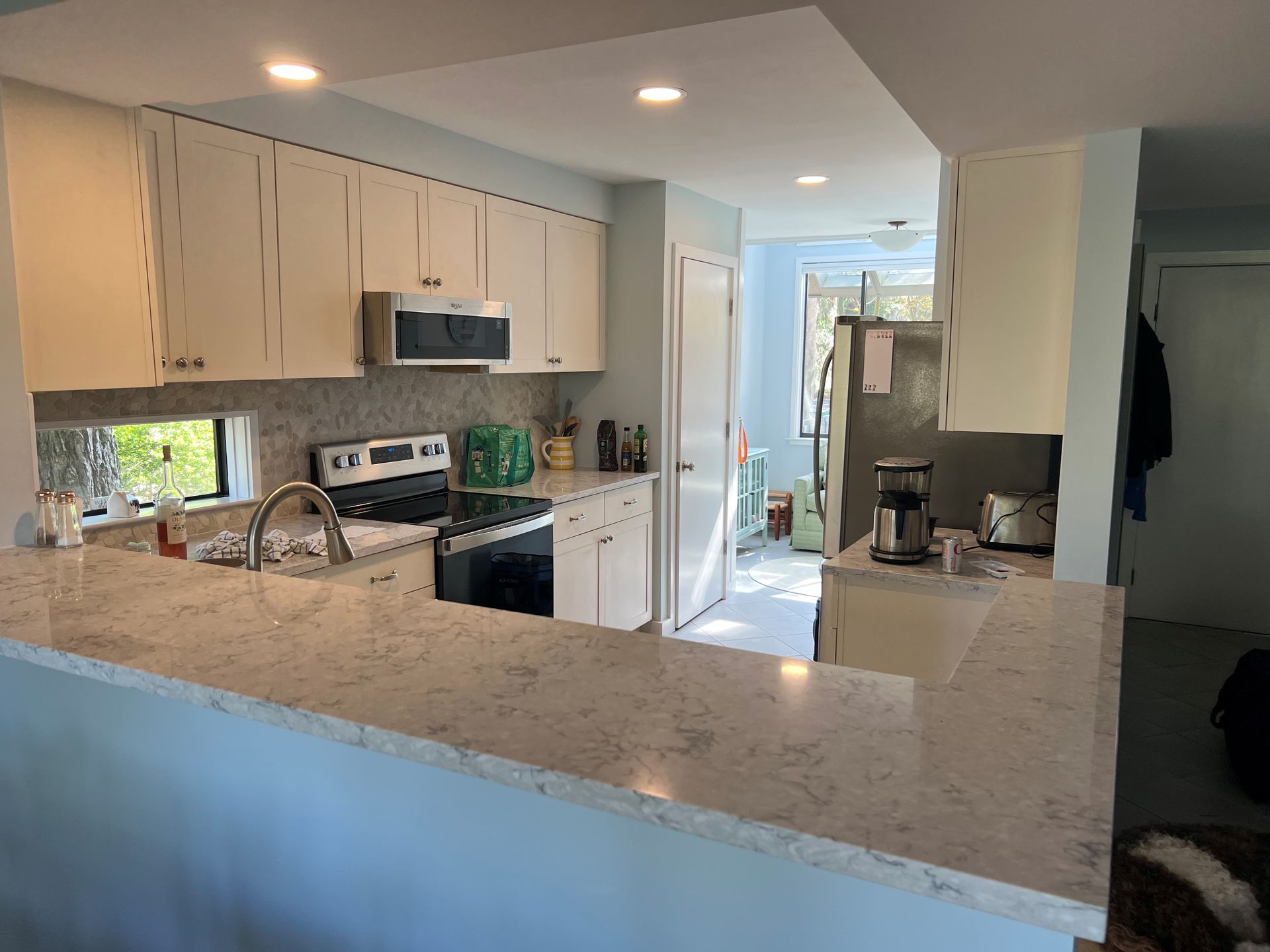 Kitchen with white cabinets, light countertops, and stainless steel appliances.
