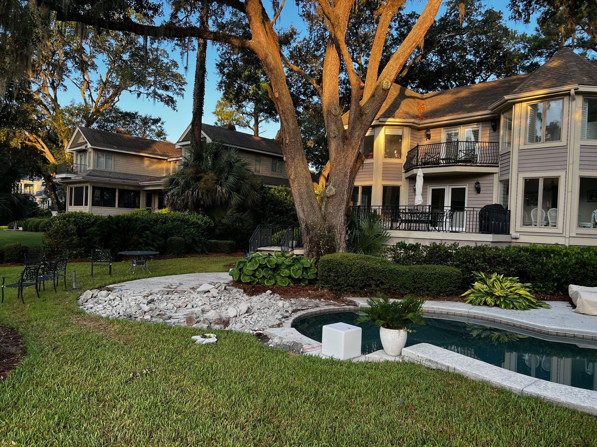 Miscellaneous Pool Projects - Lush green lawn with pool in front of large house, trees, and sky.