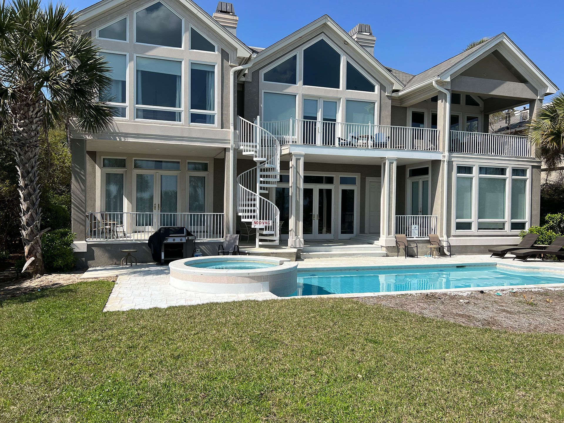 Beachfront house with a pool, two stories, large windows, and spiral staircase.