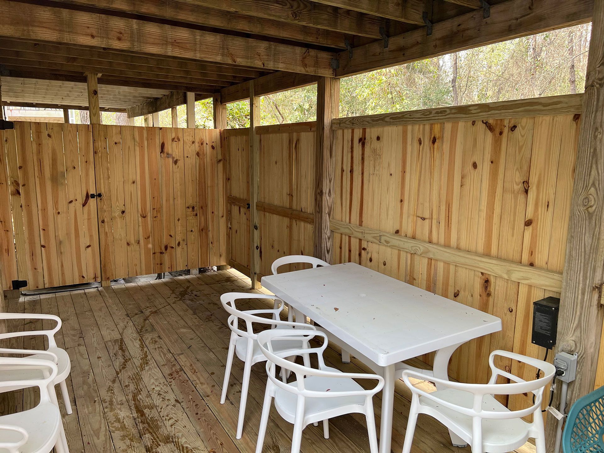 Wooden outdoor dining area with a white table and chairs.