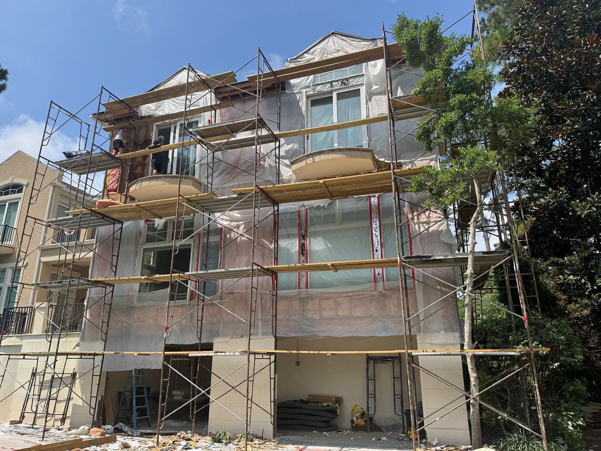Termite Damage - Building under renovation with scaffolding; exterior view with blue sky and trees.