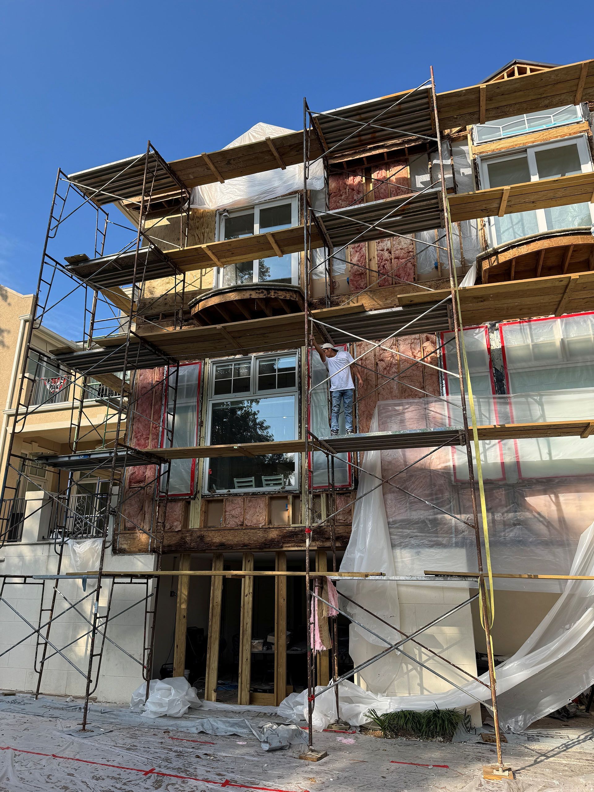 Termite Damage - Building exterior under construction; scaffolding, visible insulation, and a worker.
