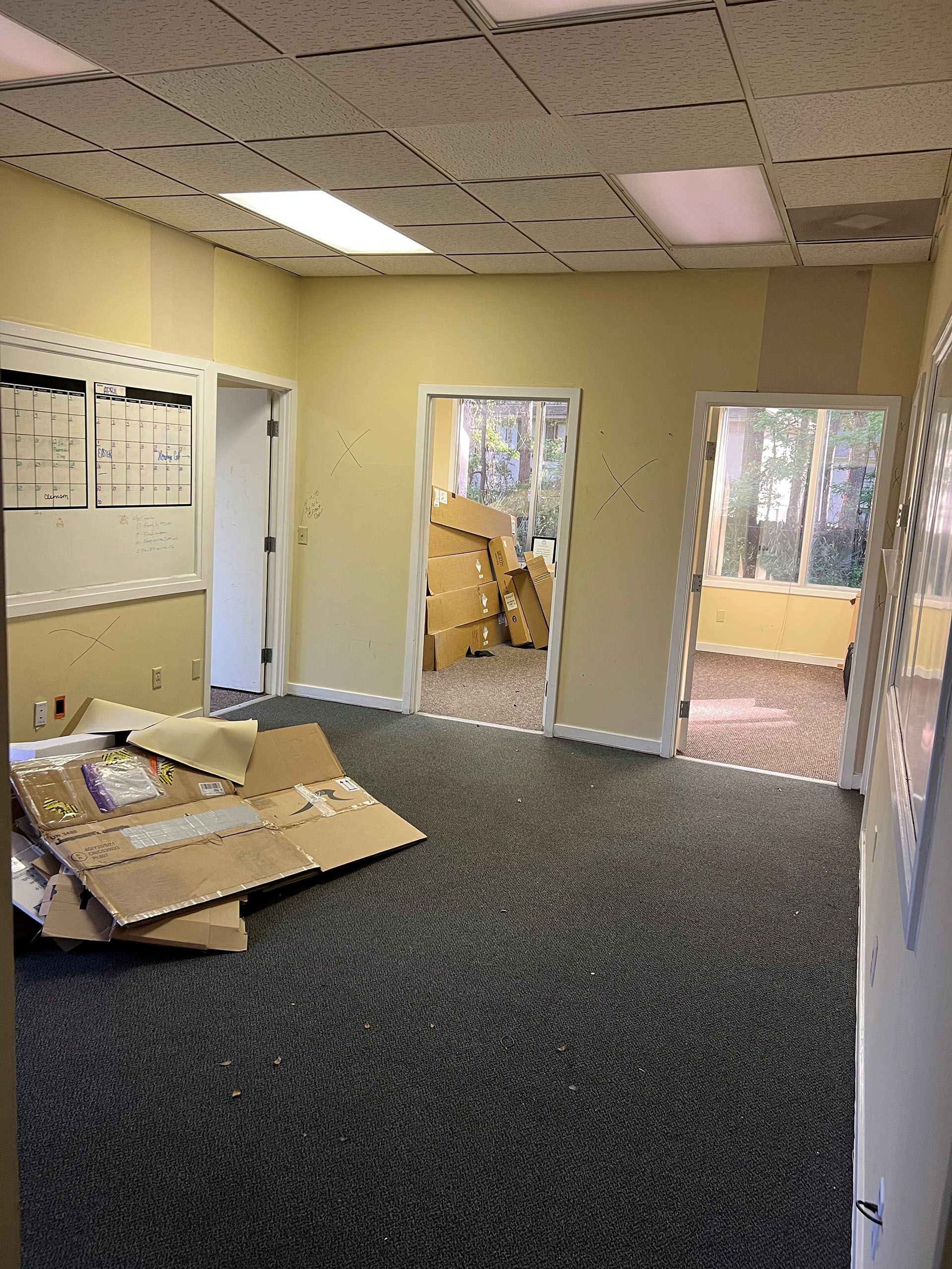 Carolina Rides - Before: Empty office with boxes, dark carpet, and three doorways.