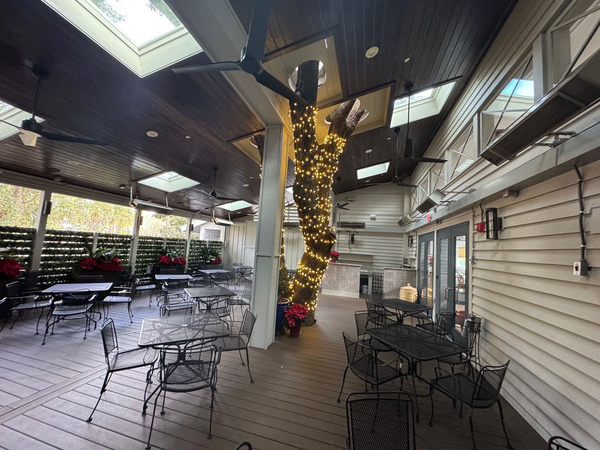 Commercial restaurant remodel and expansion  - Nunzios/After: Outdoor restaurant patio with tables, chairs, tree wrapped in lights, skylights, and heating lamps.