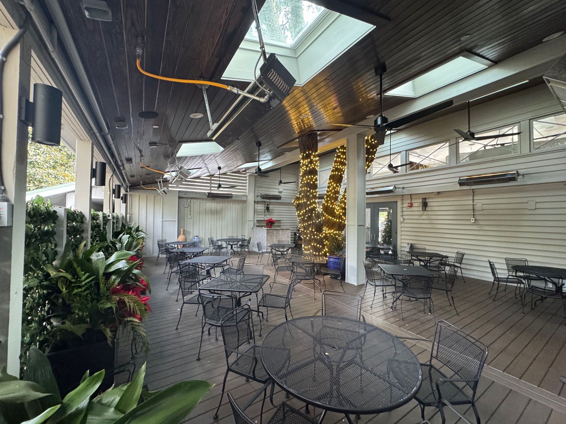 Commercial restaurant remodel and expansion  - Nunzios/After: Outdoor restaurant patio with tables, plants, string lights, and a skylight.