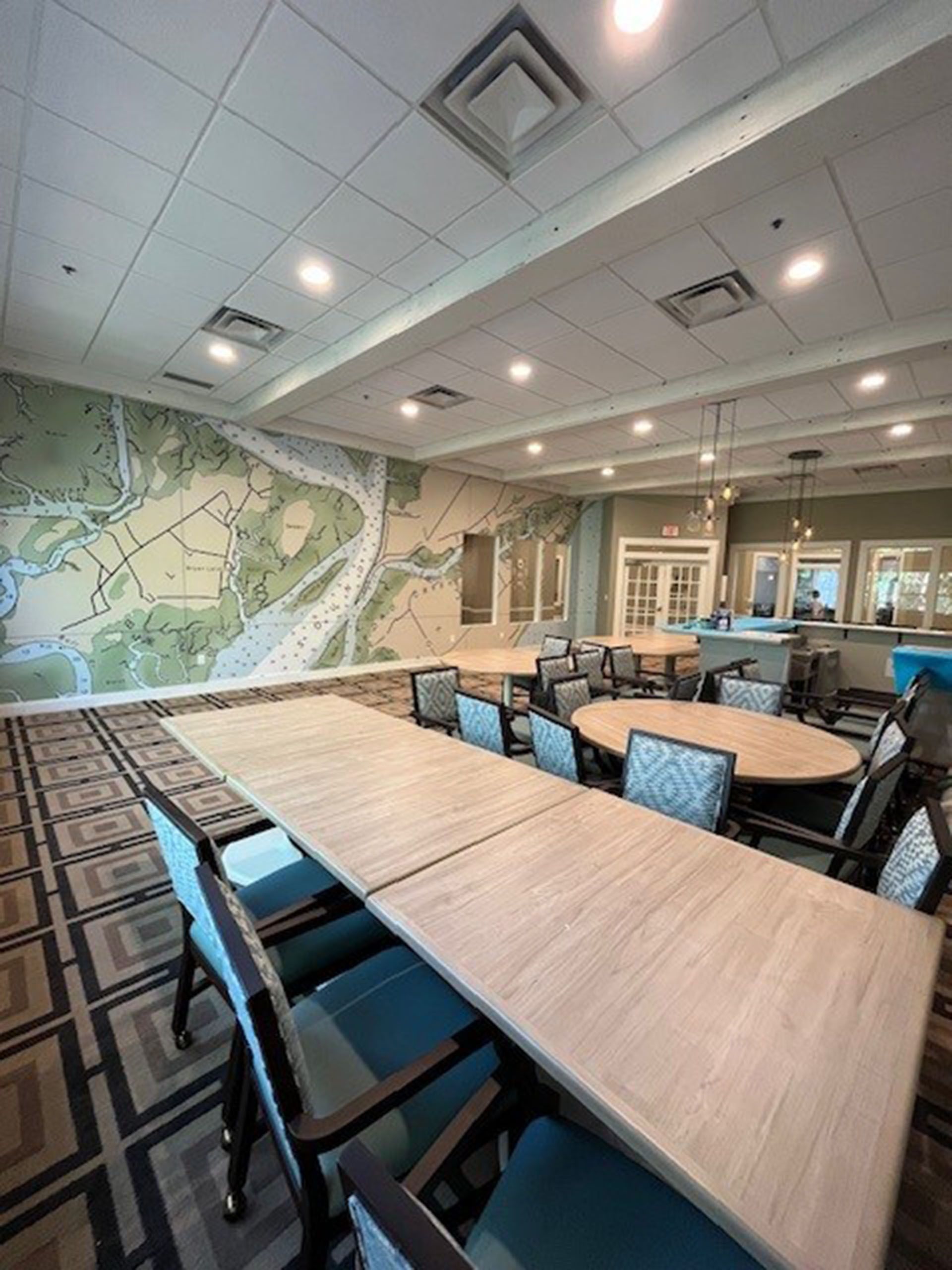 Commercial restaurant remodel and expansion - Tidepoint/After: Dining room with long table and round tables; mural on wall.