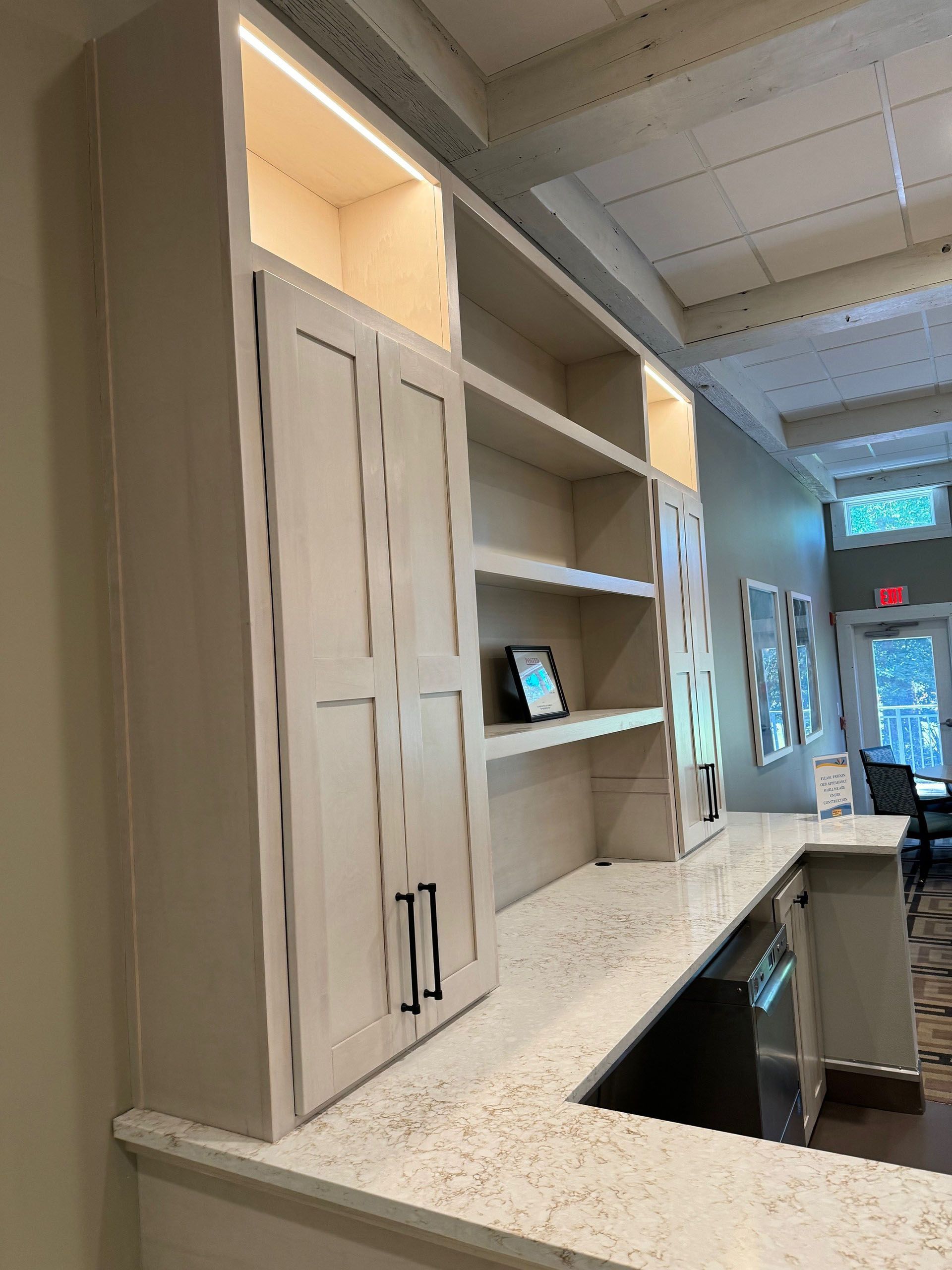 Commercial restaurant remodel and expansion - Tidepoint/After: Built-in cabinets above countertop with open shelving and closed doors. Bright lights illuminate the interior.
