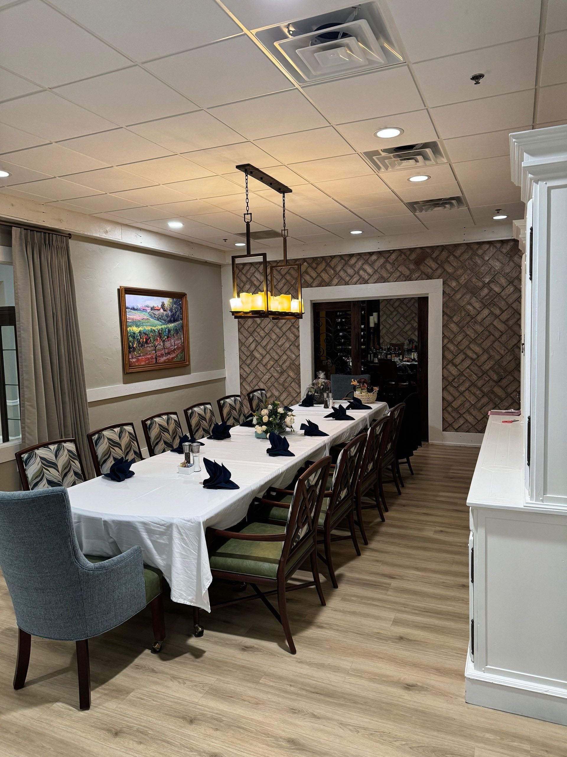 Commercial restaurant remodel and expansion - Tidepoint/After: Long dining table set for a meal, in a room with light wood floors and a decorative wallpapered wall.