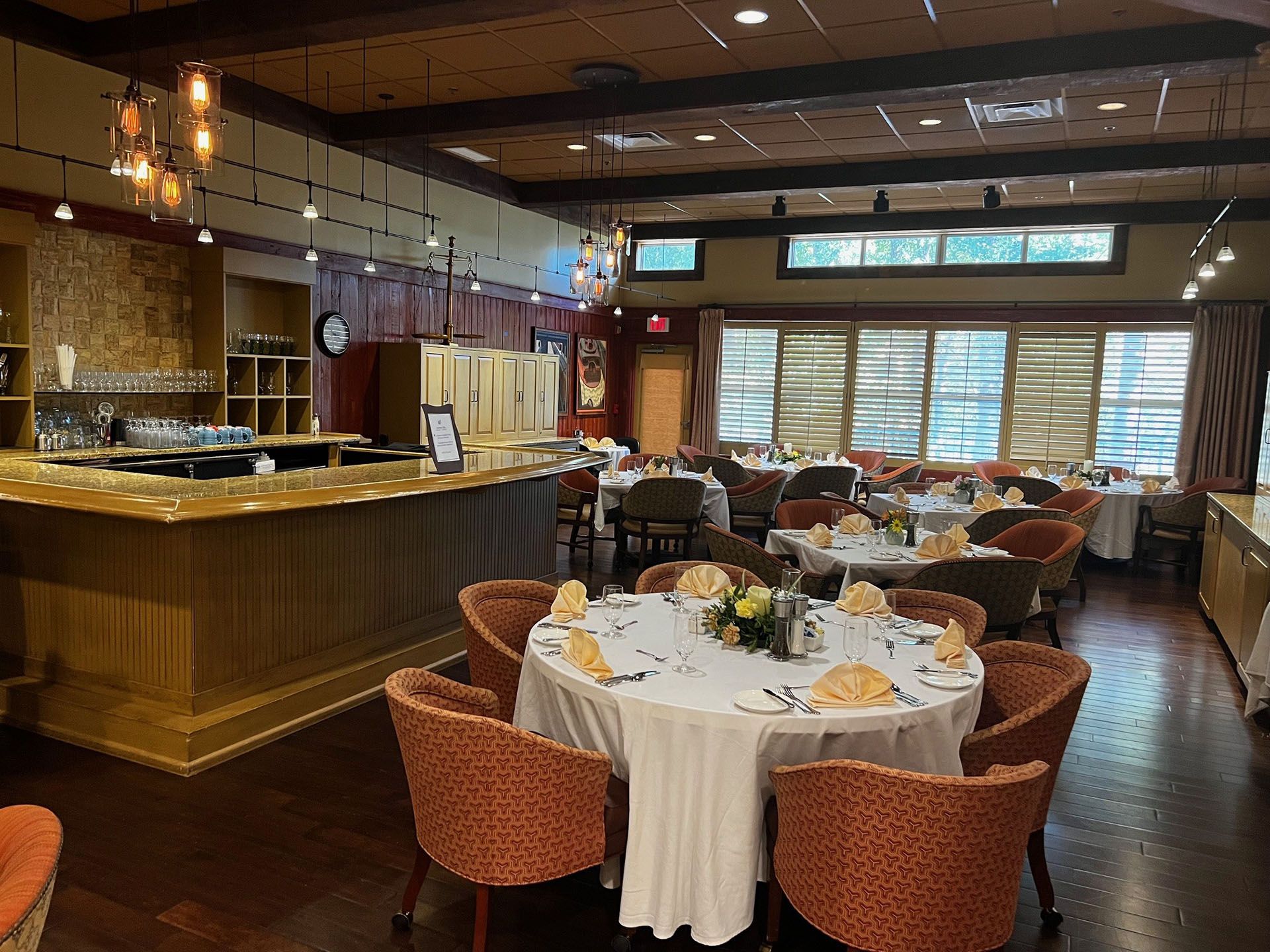 Commercial restaurant remodel and expansion - Tidepoint/Before: Restaurant interior with round tables set for dining, bar in background, wood floors, orange chairs.