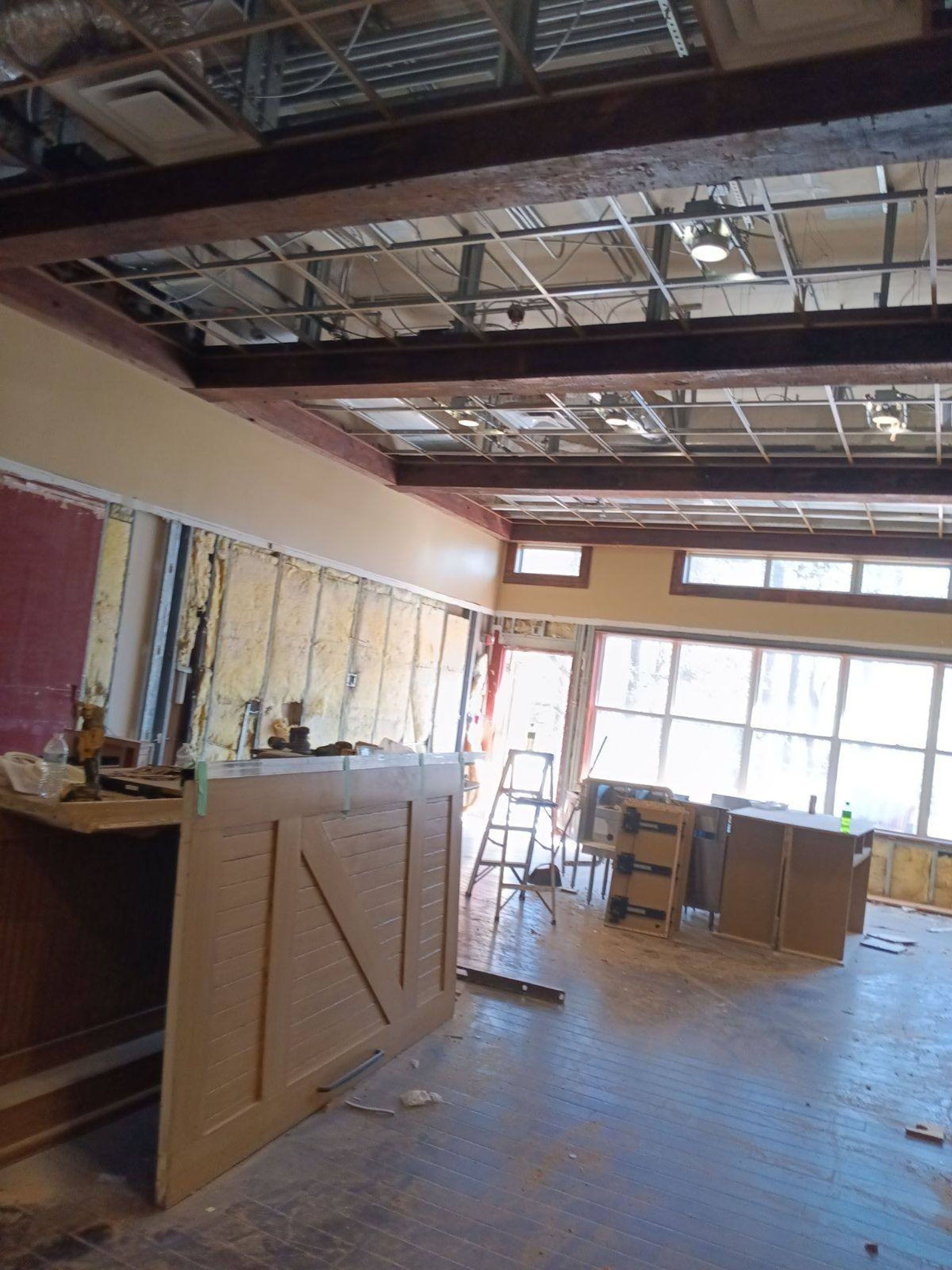 Commercial restaurant remodel and expansion - Tidepoint/During: Interior renovation site with exposed ceiling beams and walls, debris on floor.
