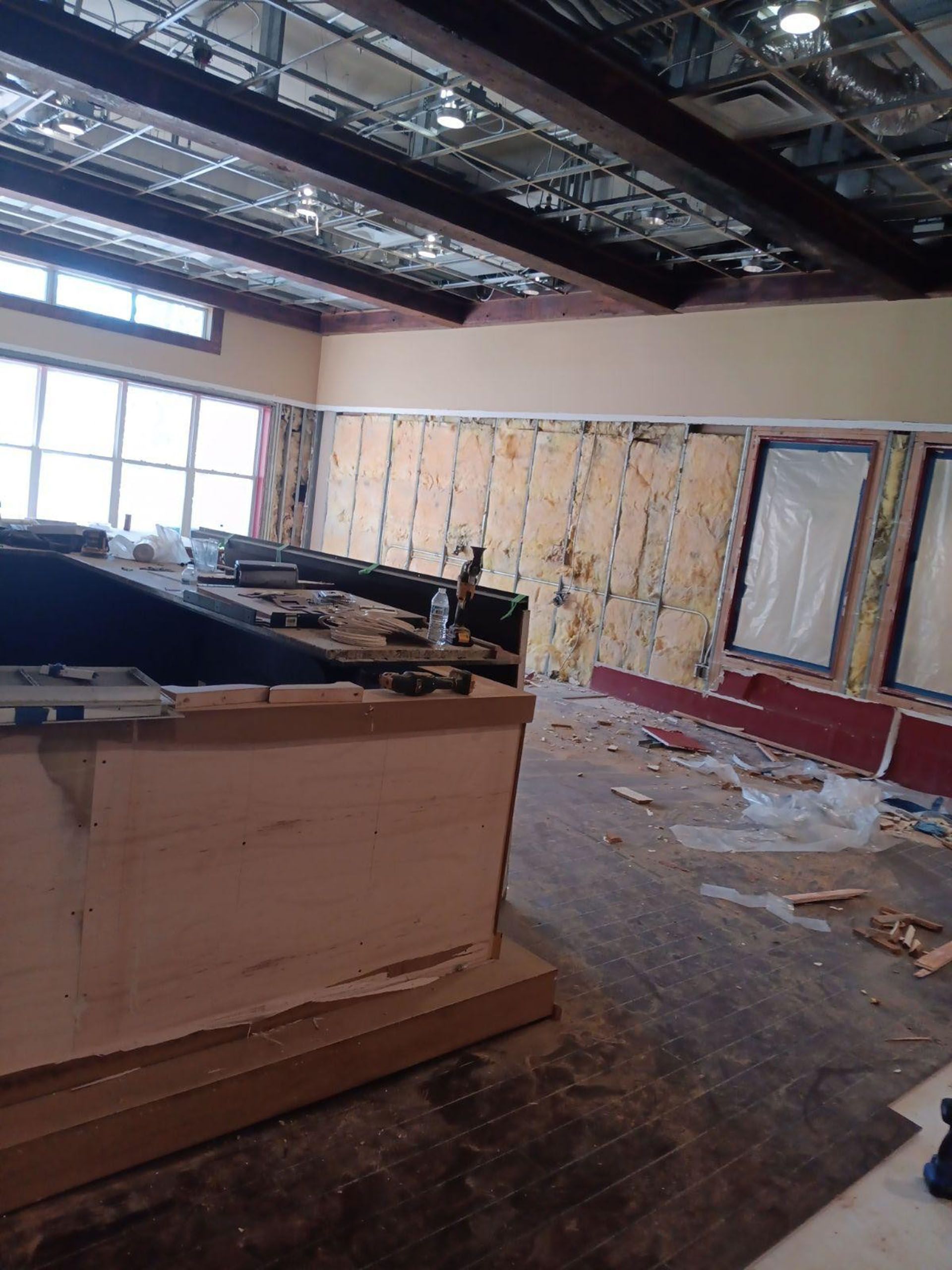 Commercial restaurant remodel and expansion - Tidepoint/During: Interior room undergoing renovation; exposed wall studs, debris, and unfinished woodwork.
