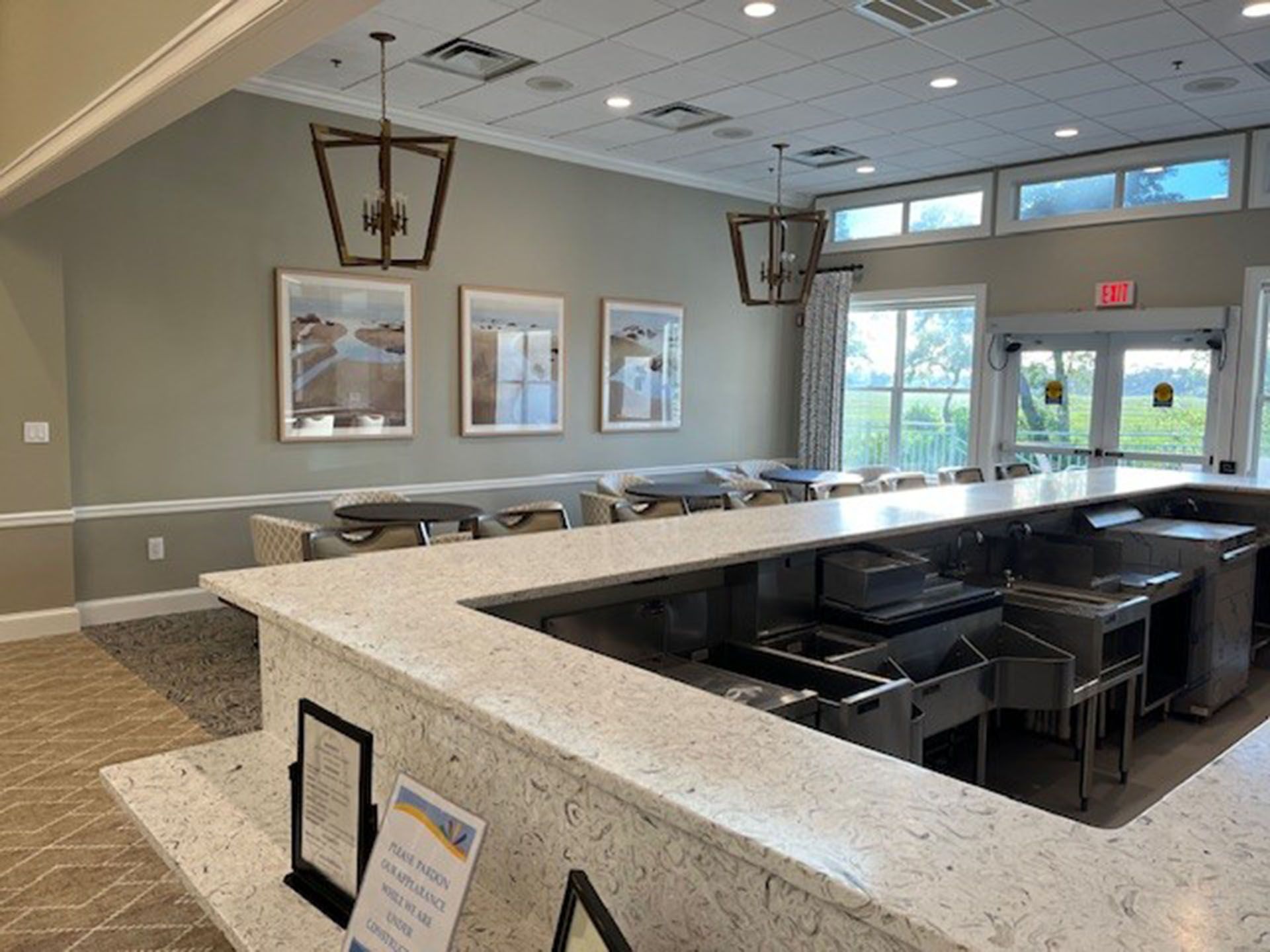 Commercial bar remodel - A bar area with quartz countertop, stainless steel equipment, and framed artwork.