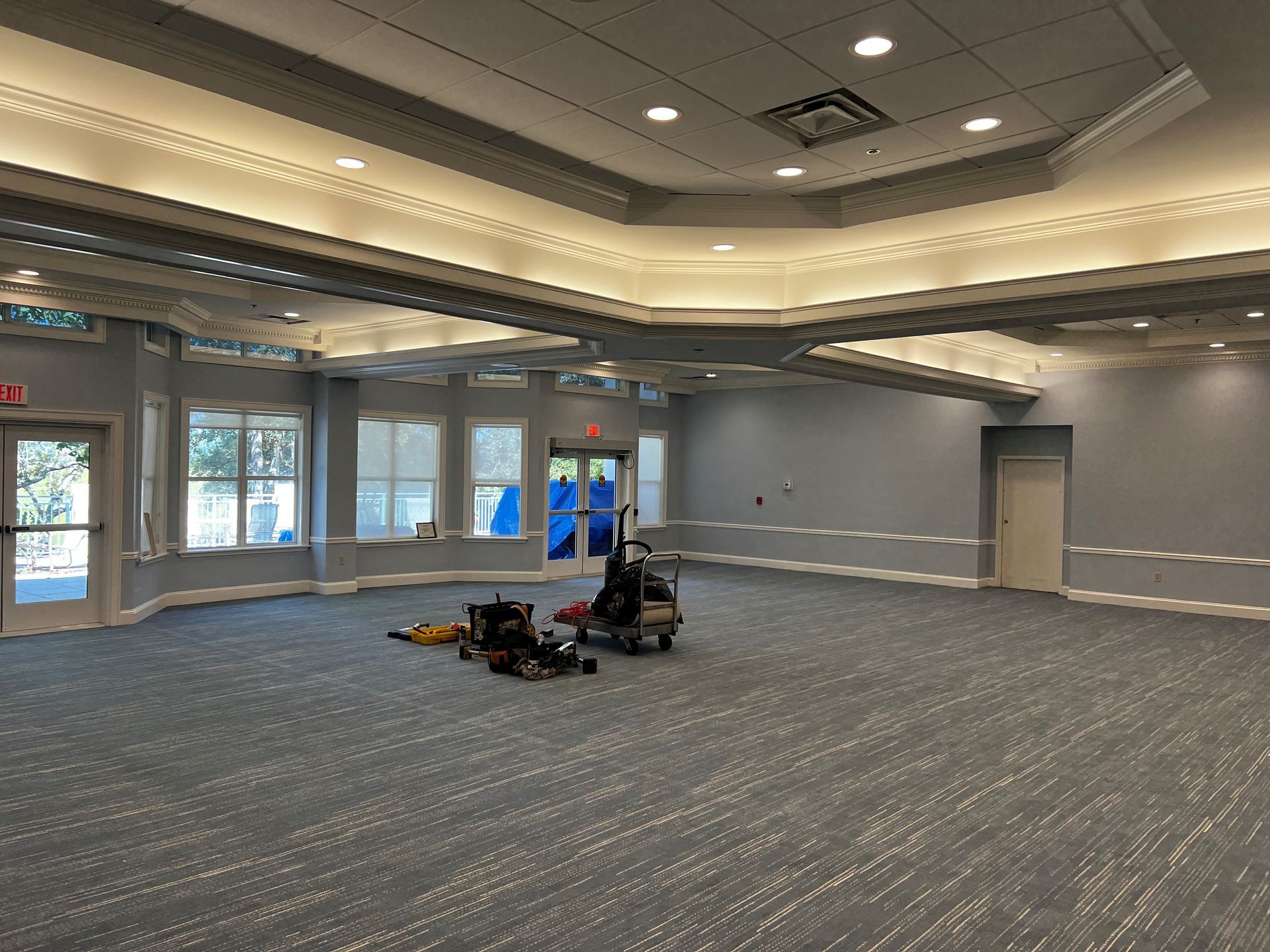 Empty event room with blue carpet, white trim, gray walls, and equipment.