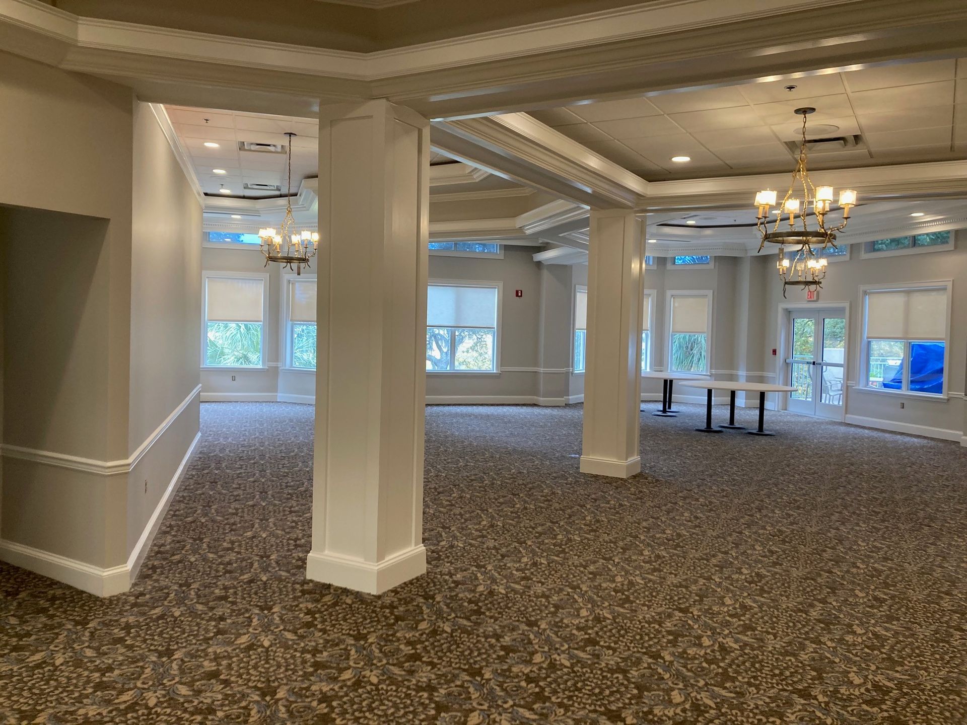 Empty event room with carpet, columns, and chandeliers