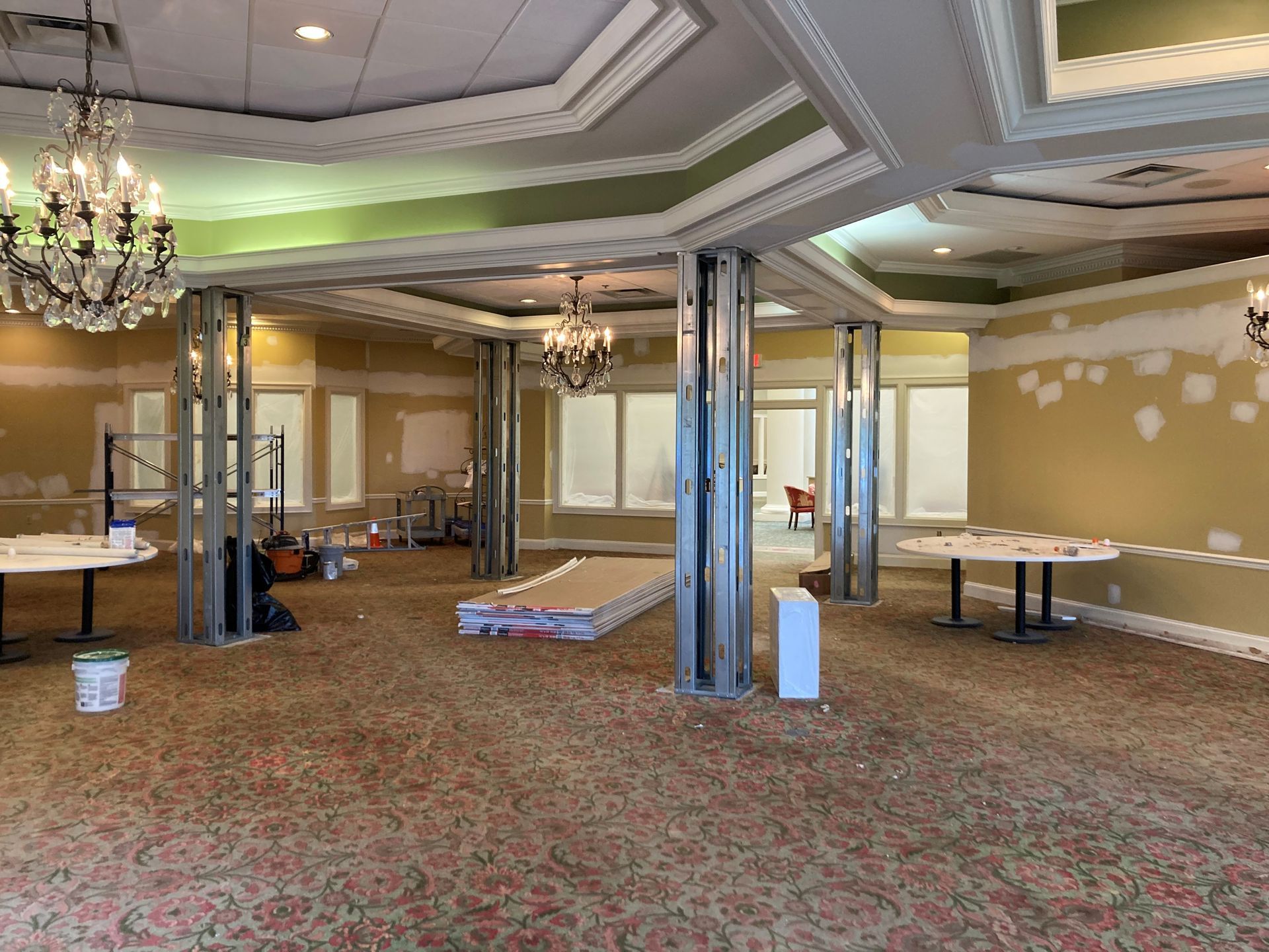 Interior of a room under renovation. Metal support beams, drywall, and partially painted walls.