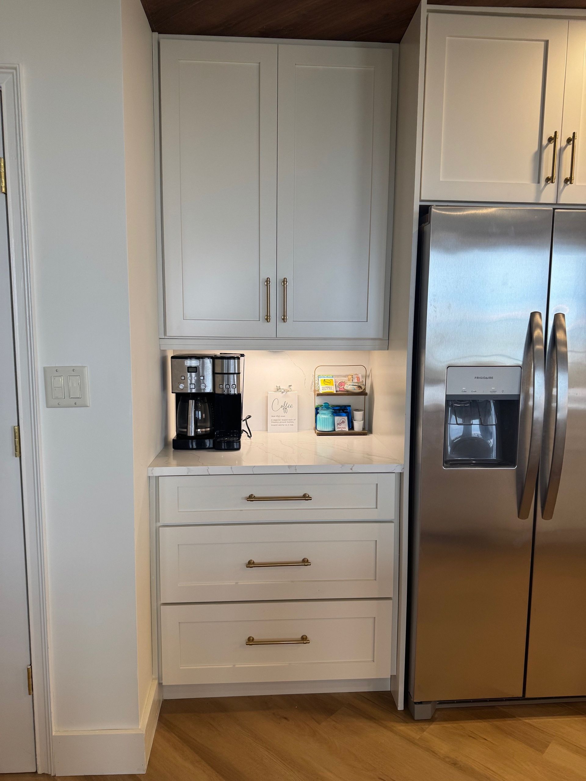 White kitchen cabinets with appliances: coffee maker, toaster, and refrigerator.