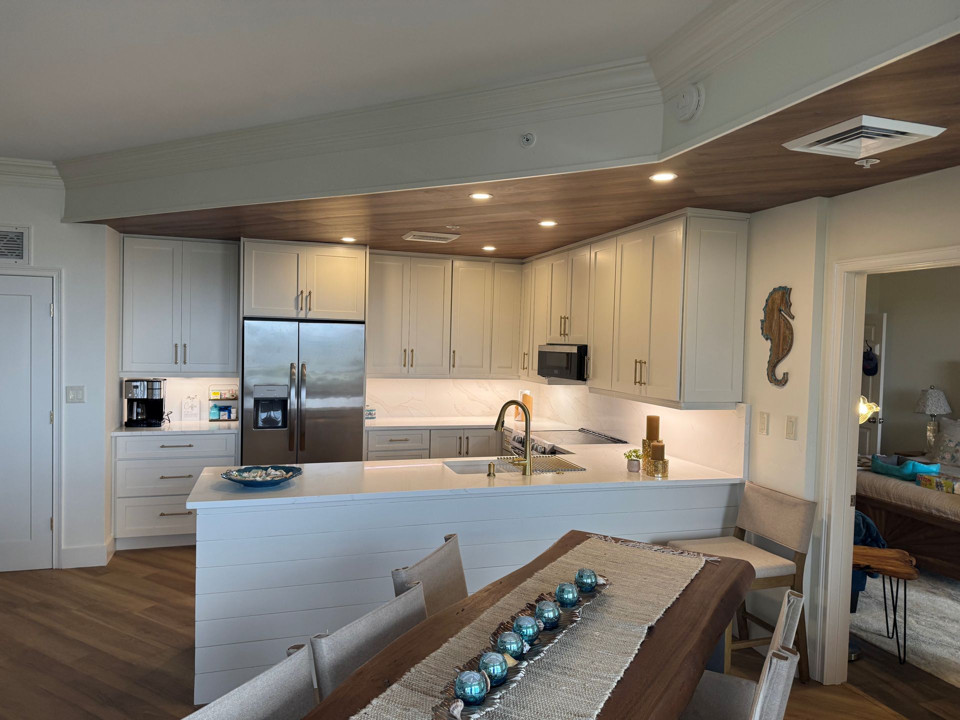 Modern kitchen with white cabinets, stainless steel appliances, and a dining island.