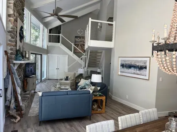 Spacious living room with high ceilings, large windows, and a staircase leading to a loft area.