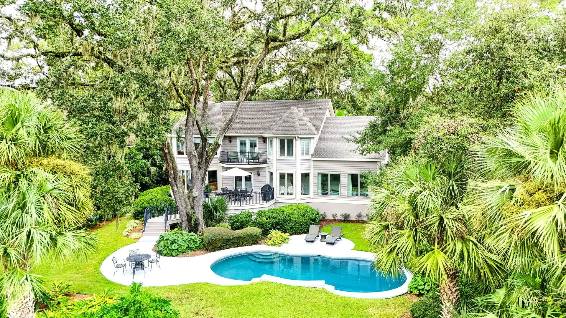 House with pool surrounded by trees.
