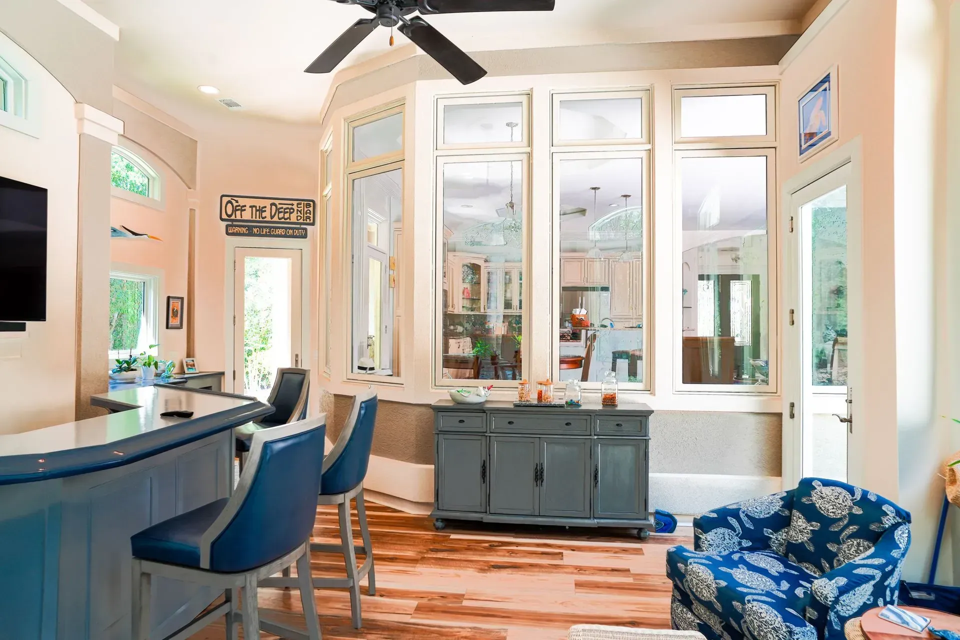 Bright, airy room with a bar, tall windows, and a blue armchair.