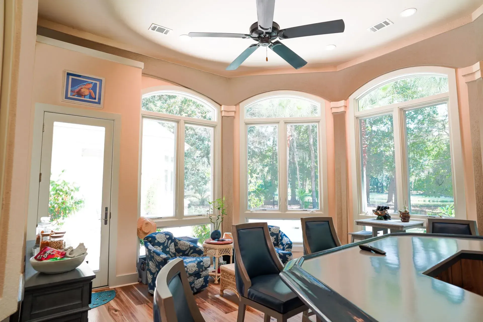 Sunlit dining area with large arched windows, bar seating, and a door to the outside.